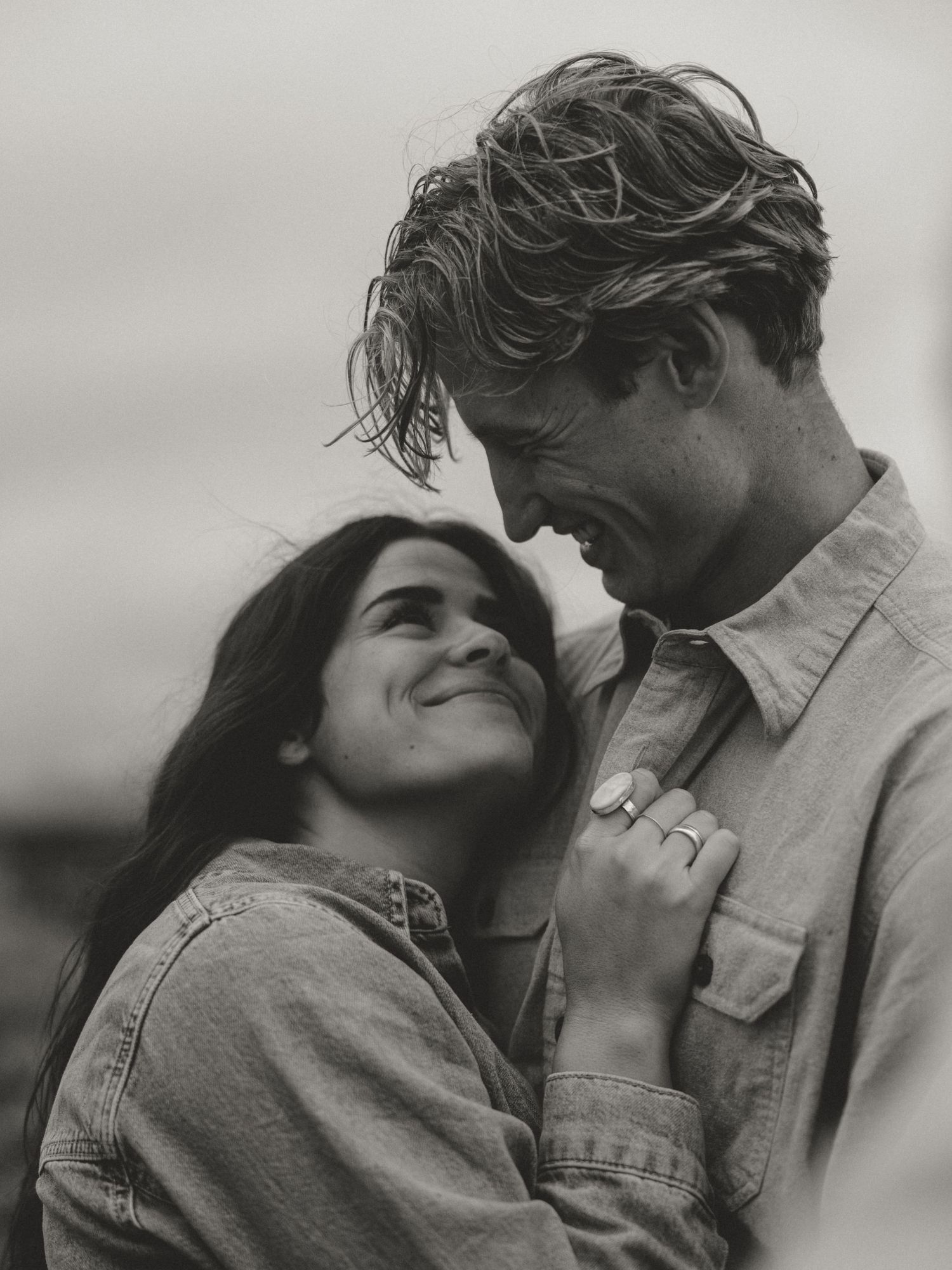 A black and white portrait of a couple sharing a tender moment outdoors.