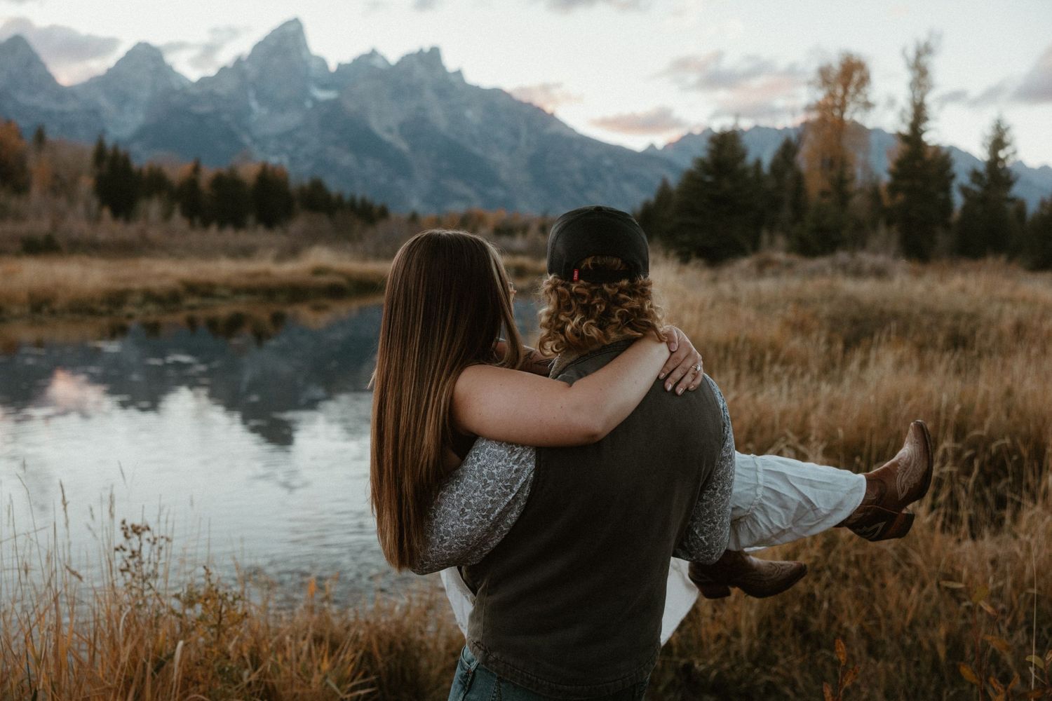 Mountain landscape with lake reflections and couple in romantic embrace.