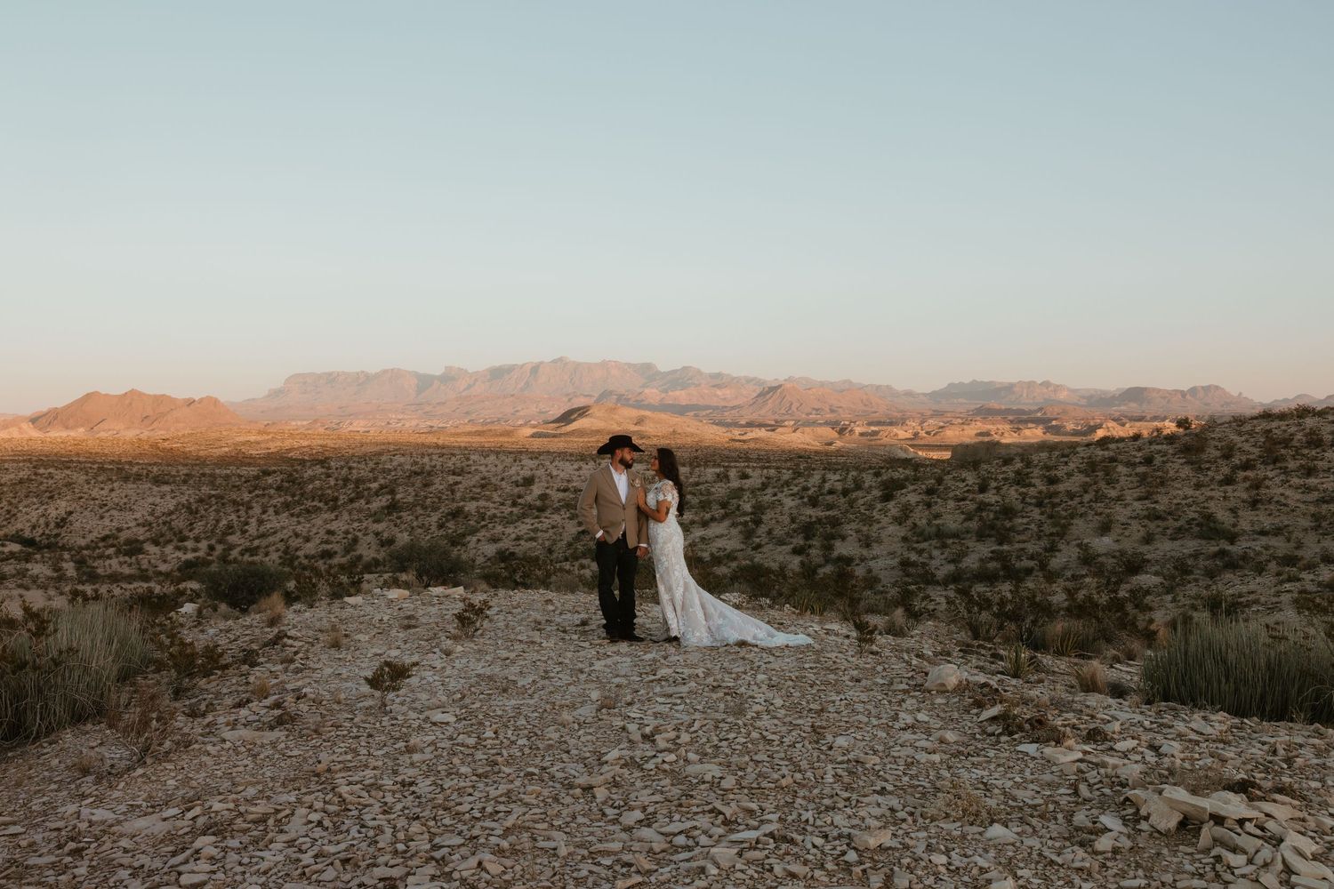 Desert landscape at sunset with mountains and rocky terrain during a wedding ceremony.