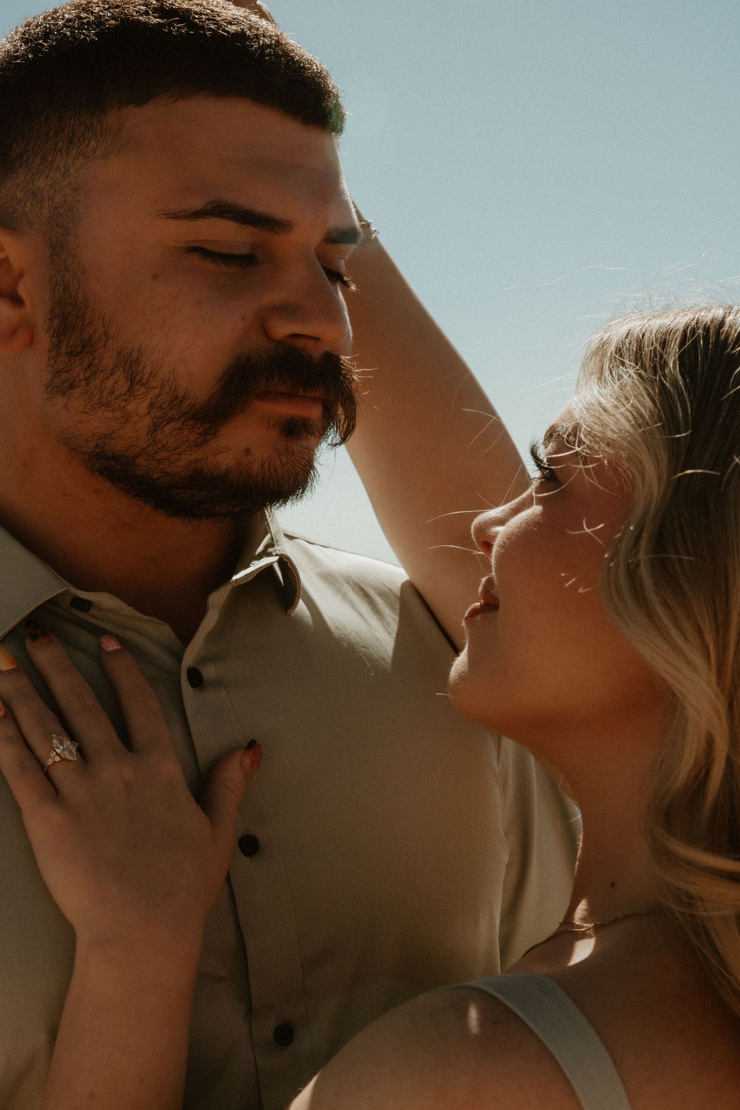 Intimate close-up portrait with warm golden lighting and tender emotional connection.