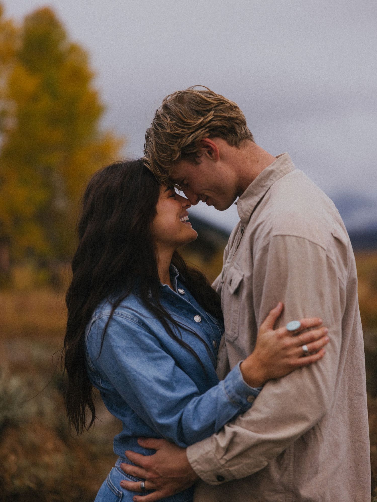 A romantic embrace captured against an autumn landscape with mountains in the distance.