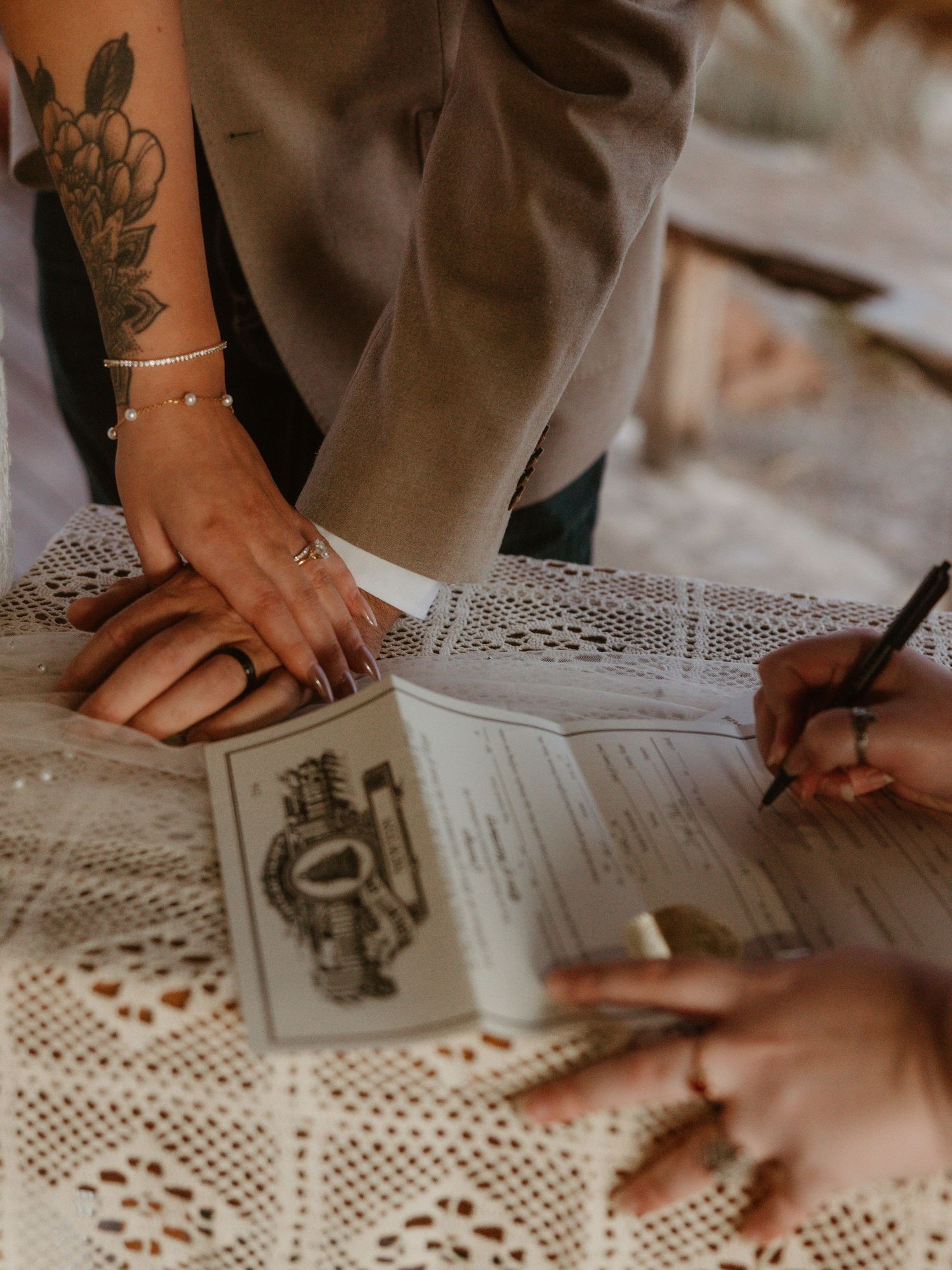 Close-up view of hands working on a lace doily surface with vintage-style illustrations and sketches.