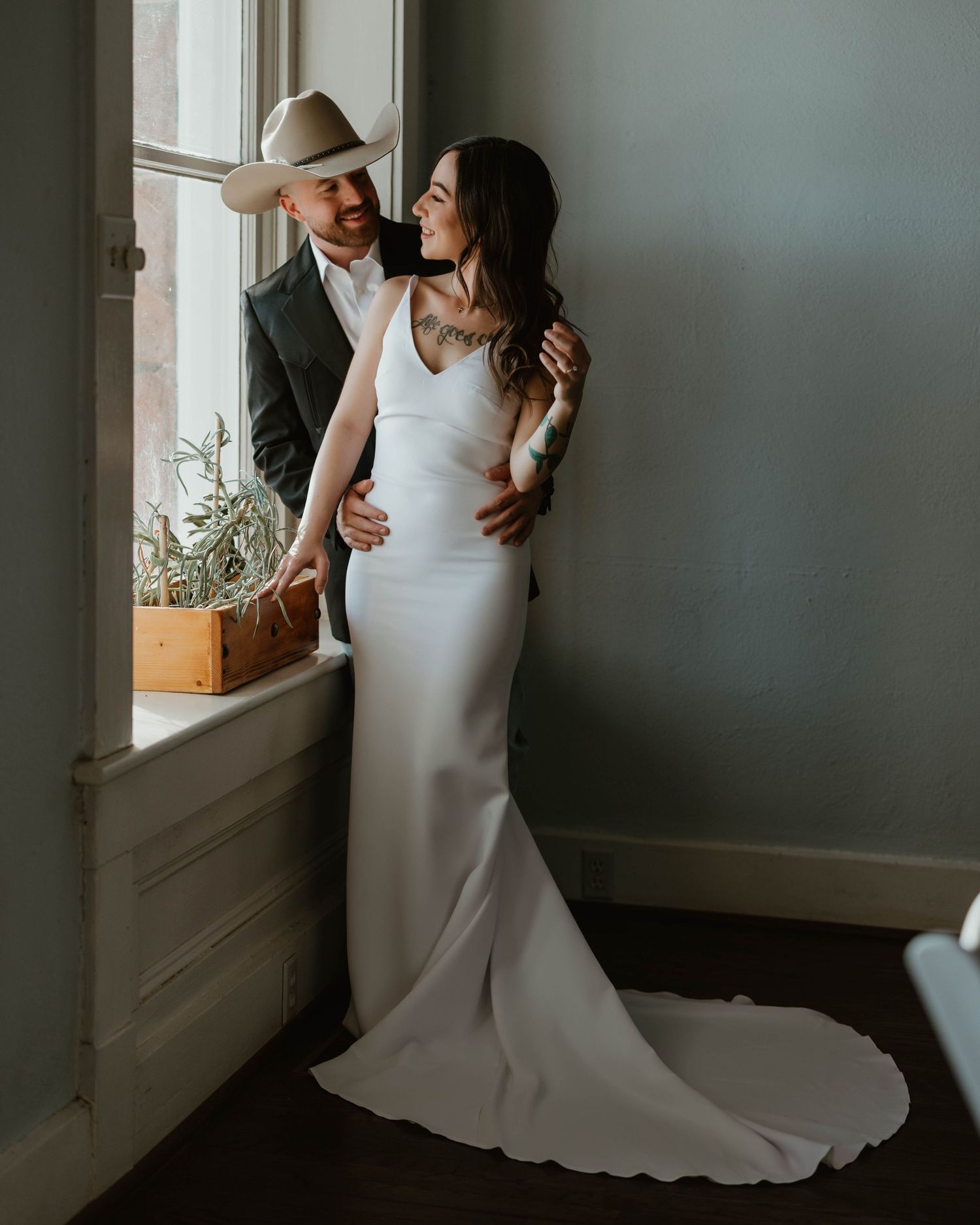 Intimate wedding moment captured by window with natural light streaming in.