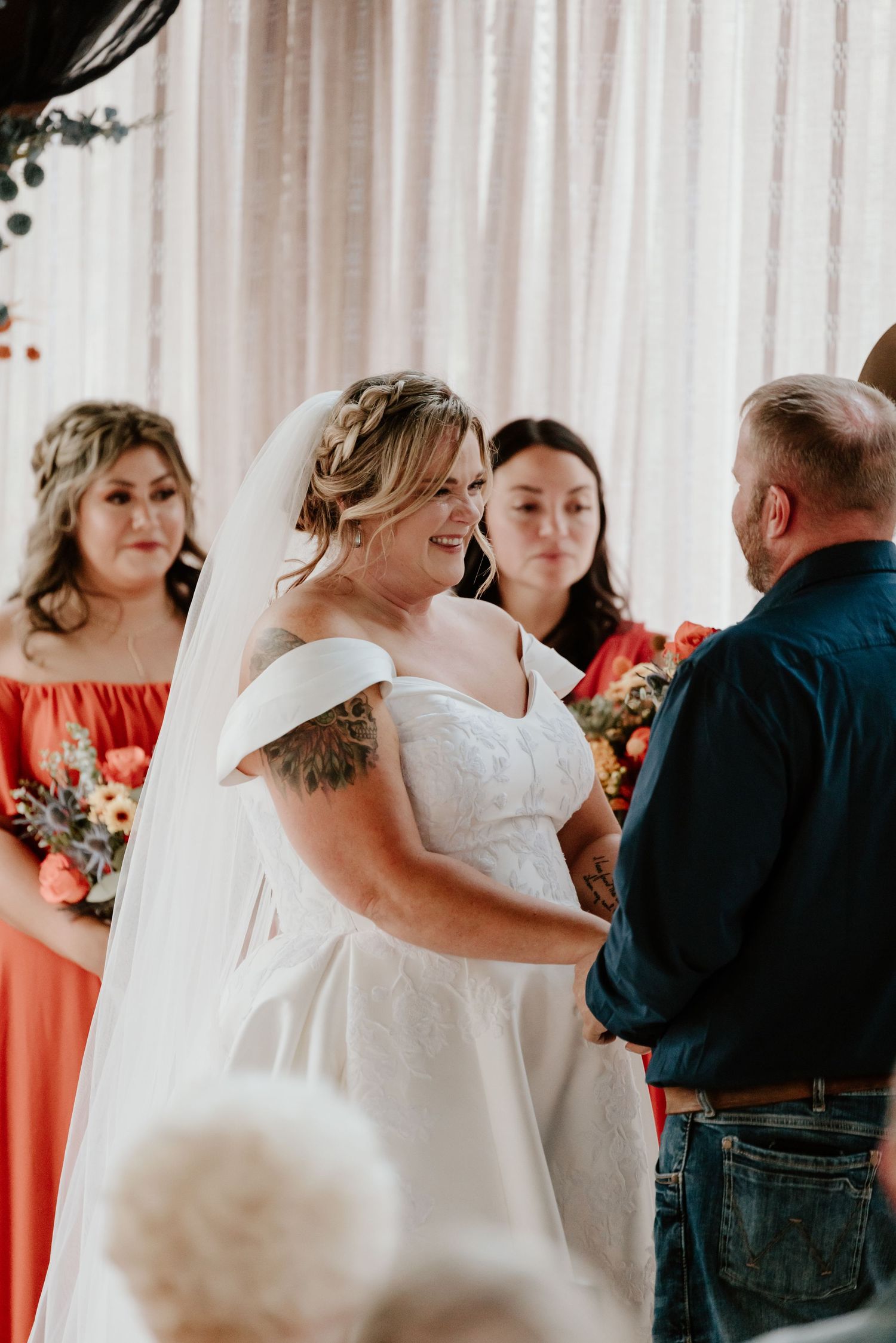 Wedding party poses in white and coral attire against a light backdrop.