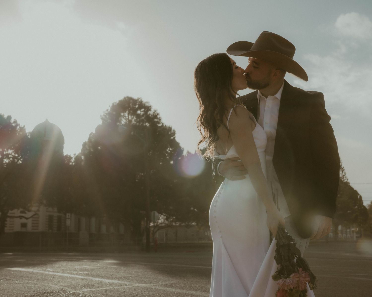 Sunset wedding photos with dramatic lighting and silhouettes against a rural backdrop.