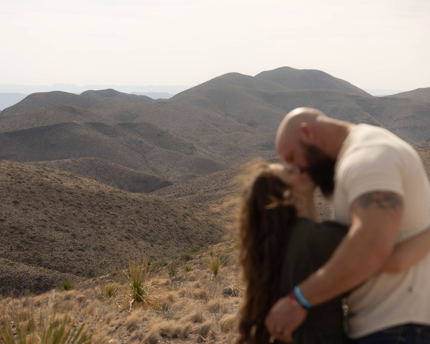 Romantic desert photoshoot featuring a couple dancing against mountainous terrain.