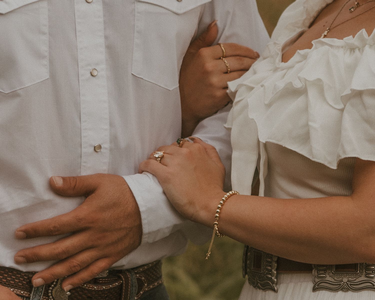 Close-up detail of couple in white clothing embracing outdoors.