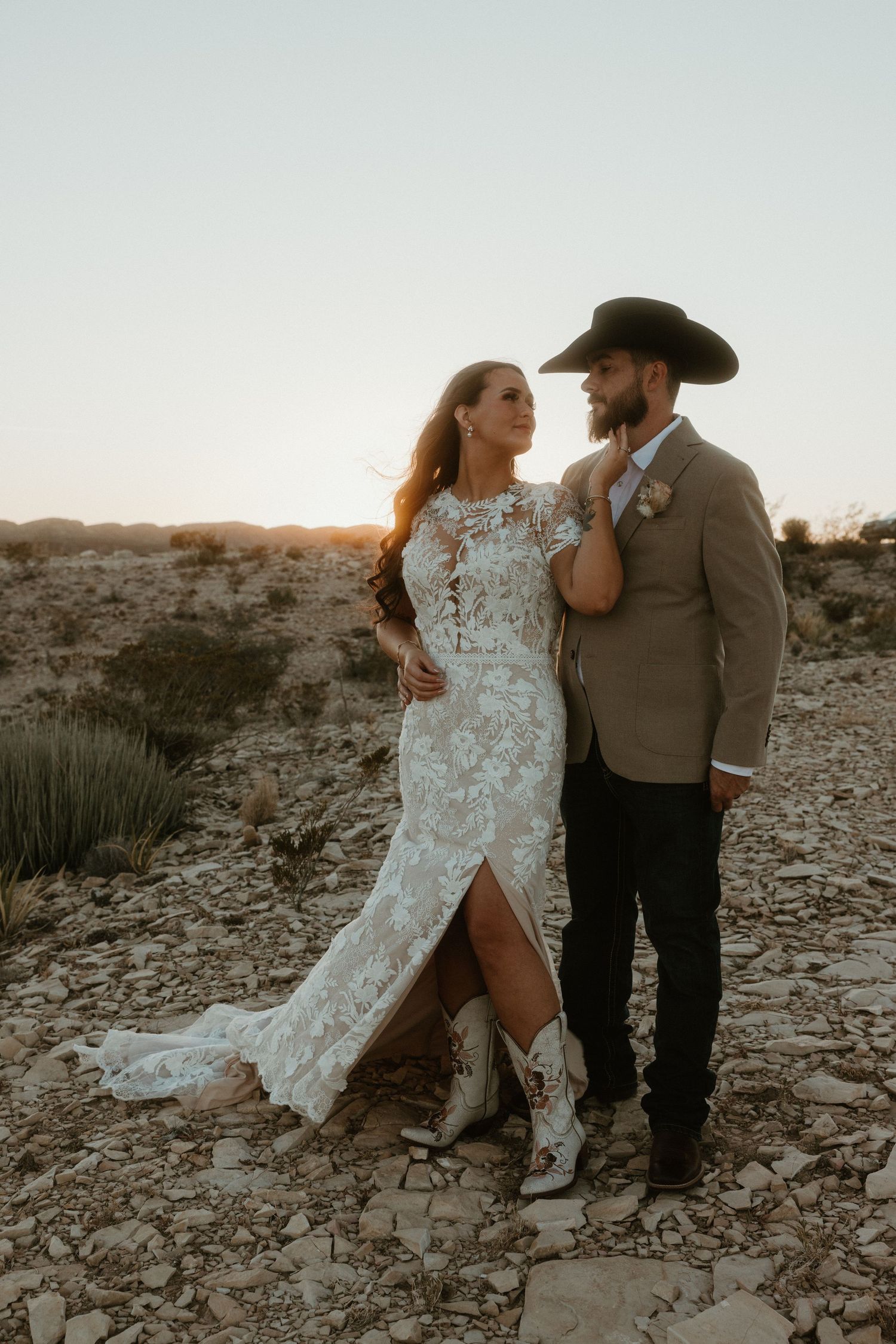 Romantic desert wedding portraits at sunset with couple in formal attire.