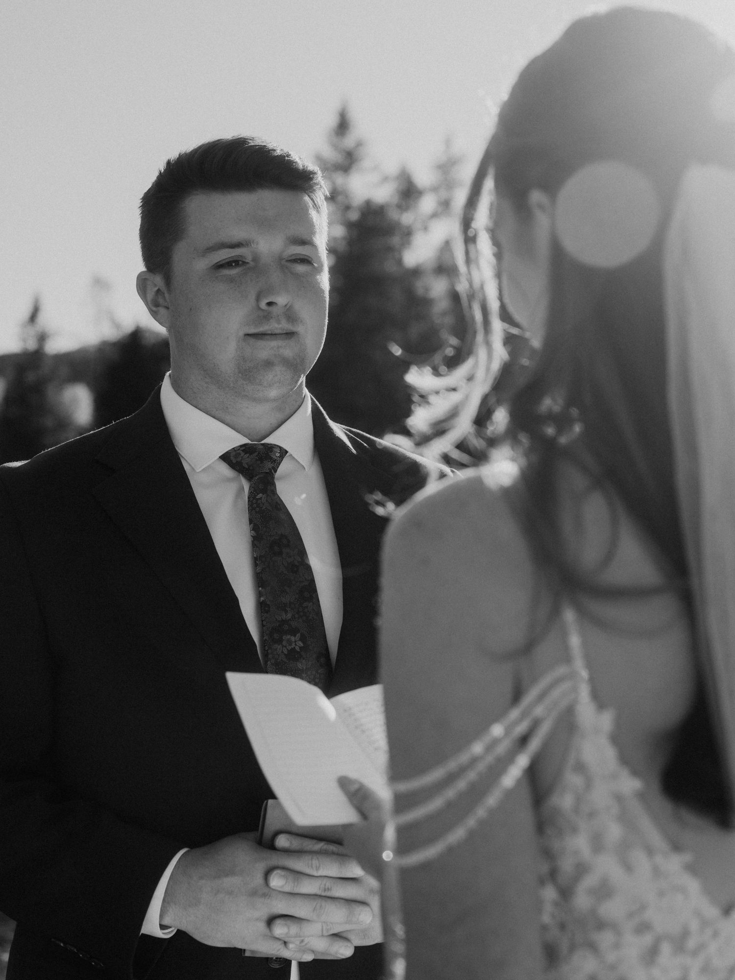 Wedding ceremony moment with emotional vow reading in natural outdoor setting.