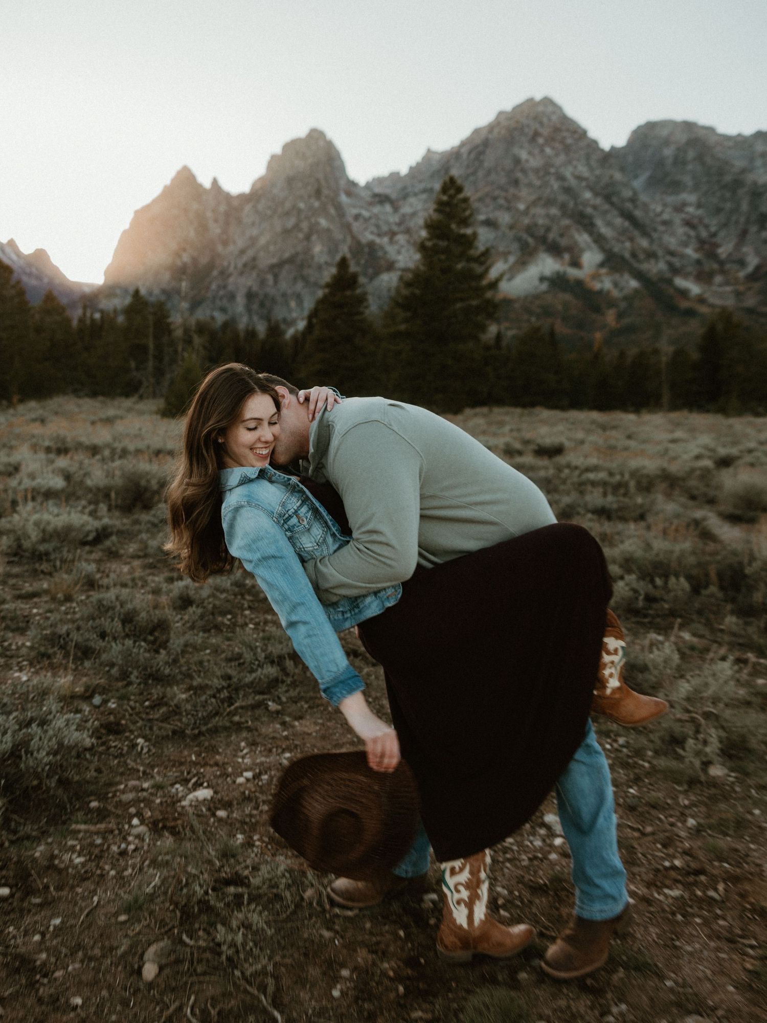 Romantic dip pose with mountains and sunset creating dramatic backdrop.