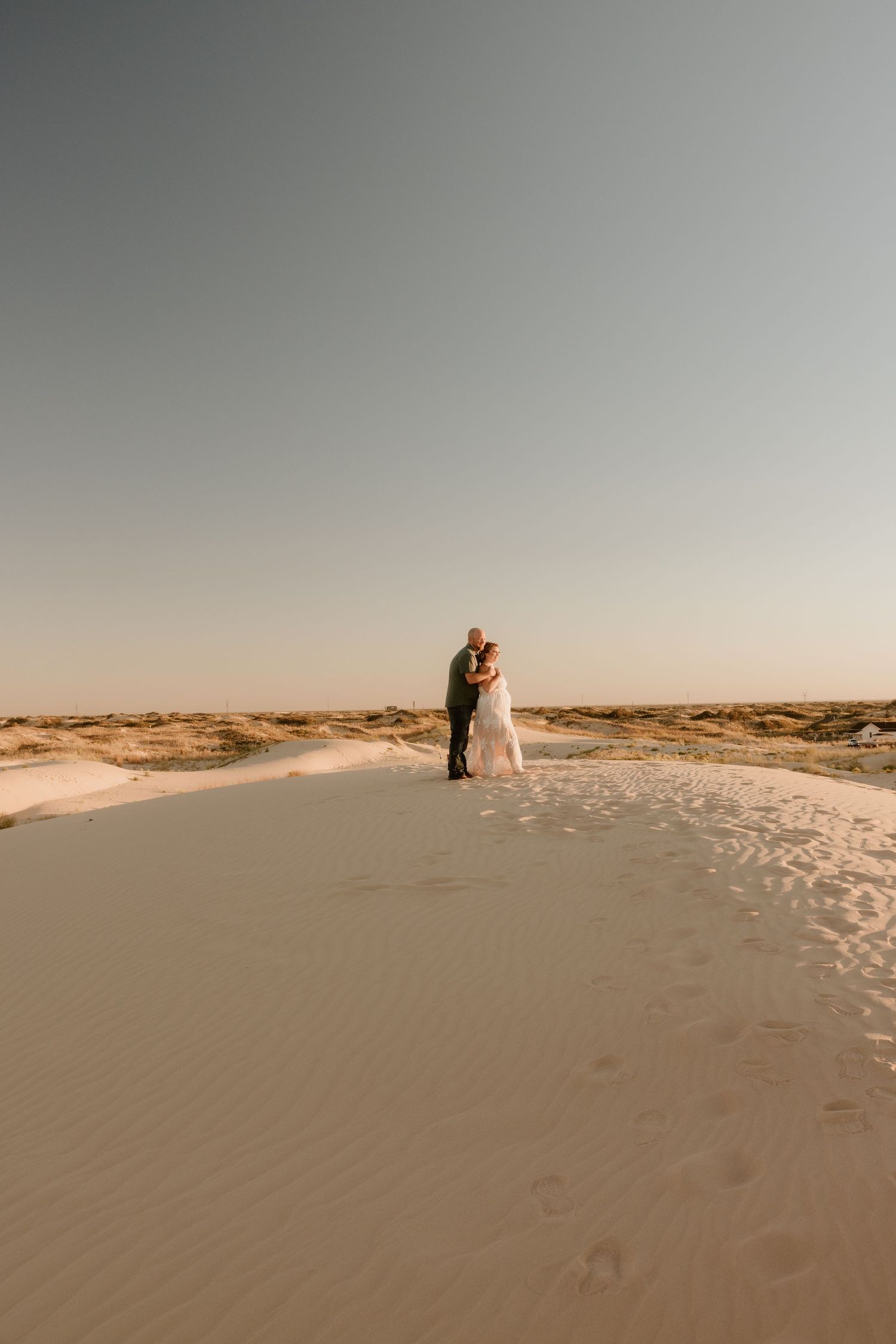 A romantic desert wedding photo with silhouettes against a sunset sky.
