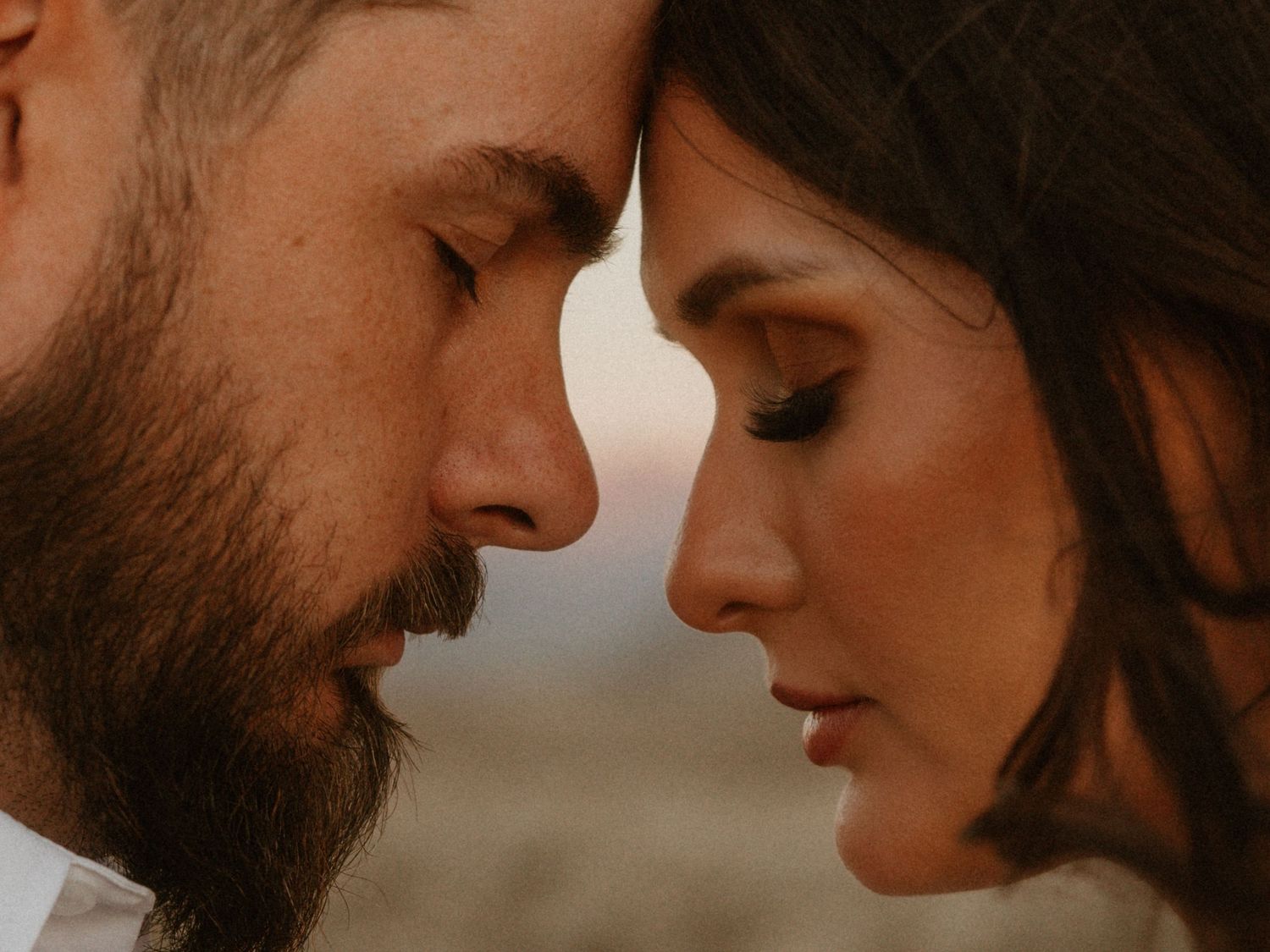 Close-up romantic portrait of couple with foreheads touching.