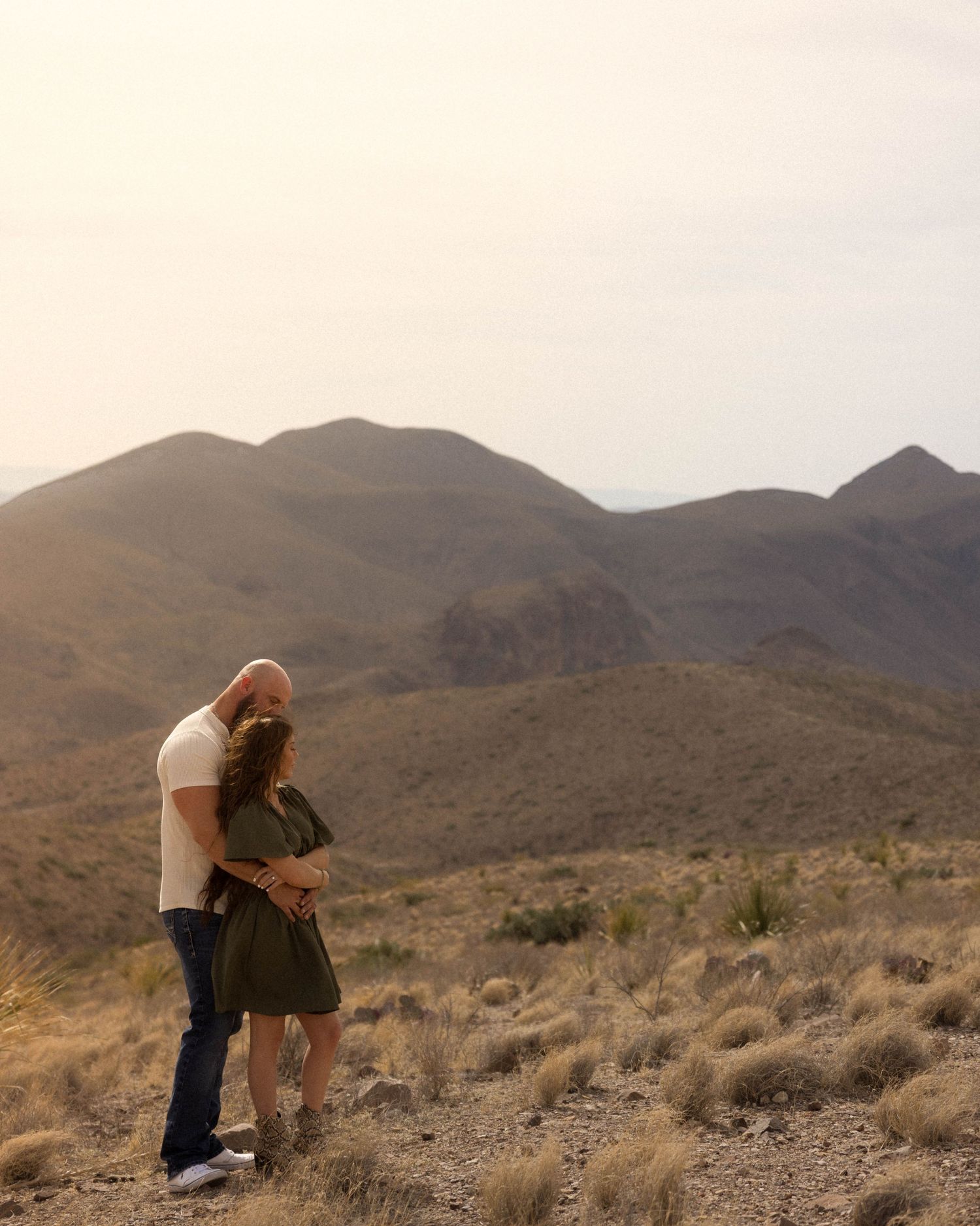 Intimate couple's photoshoot in a desert mountain landscape during sunset.