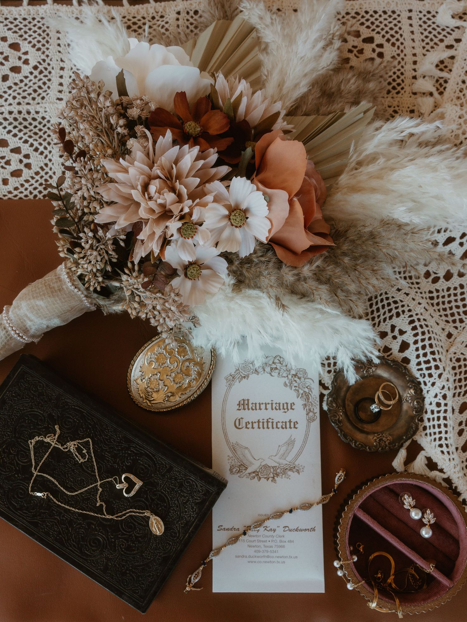 Wedding details flatlay with marriage certificate, flowers, and vintage decor.