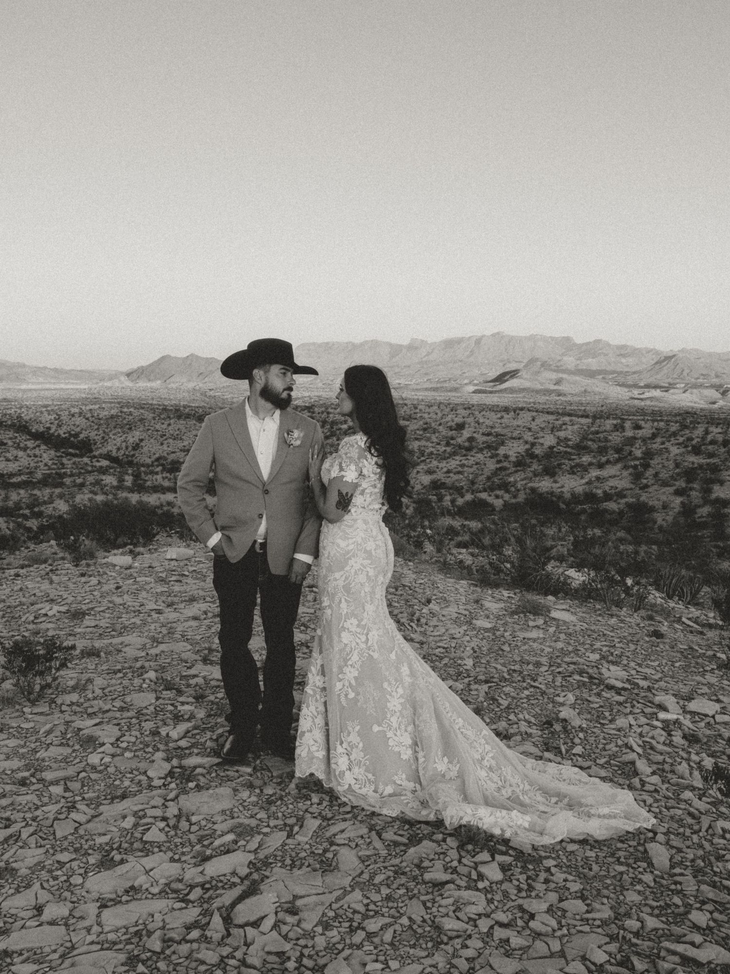 Black and white desert wedding portrait with dramatic mountain landscape.