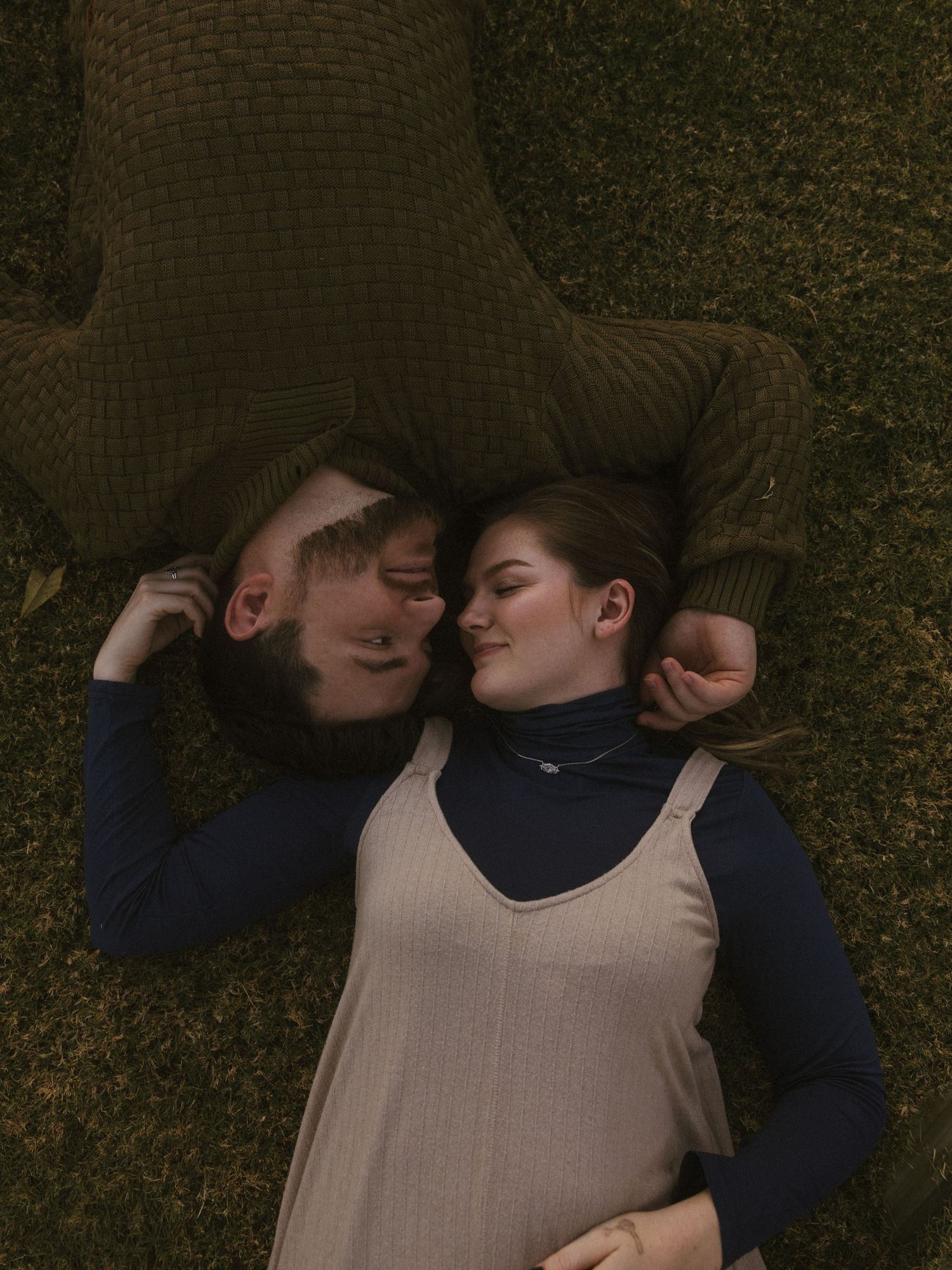 Couple sharing tender moments while lying on grass together.