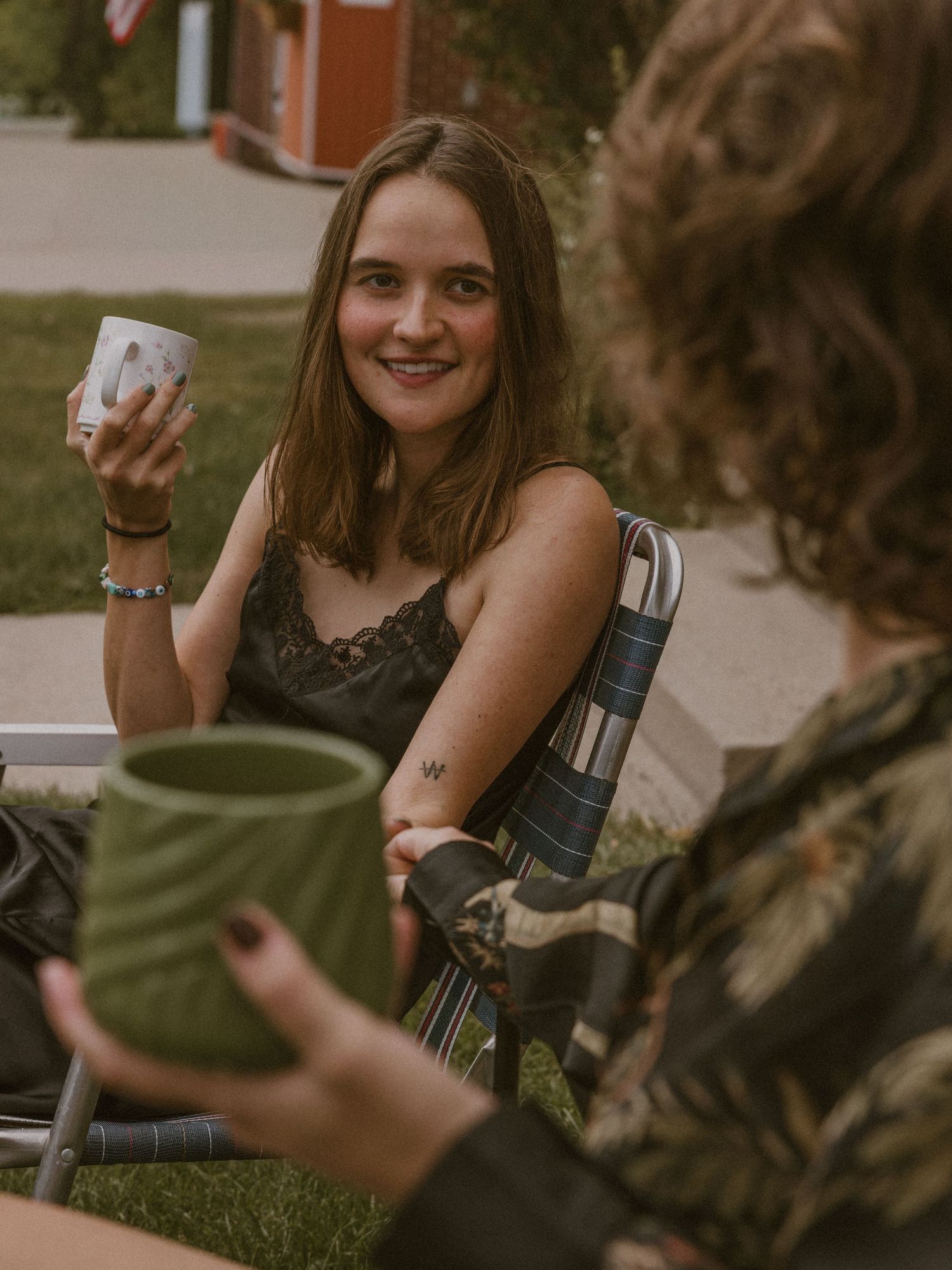 Friends enjoying coffee and conversation outdoors on a sunny day.