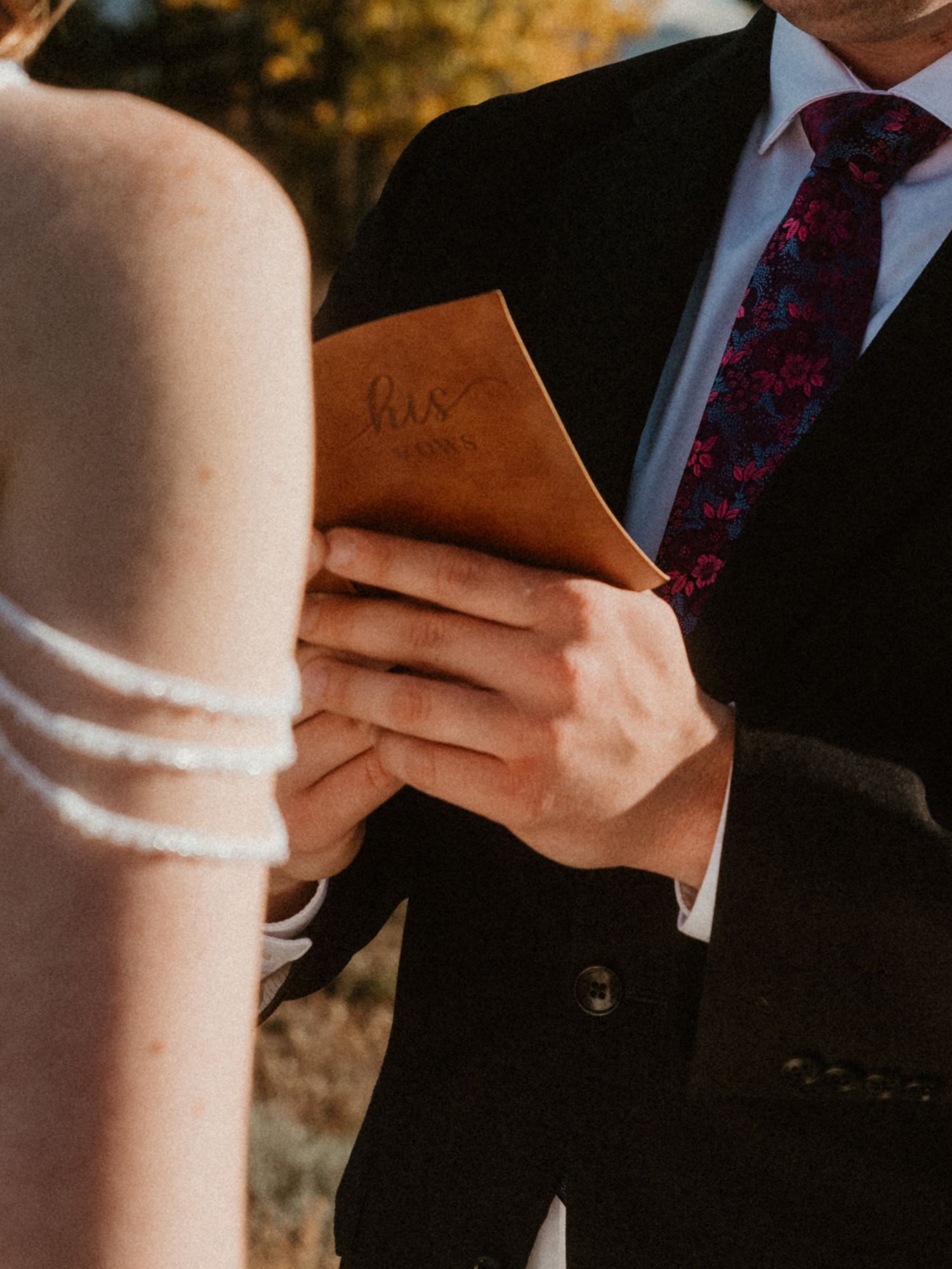 Close-up detail of wedding vows being read from small brown notebooks.