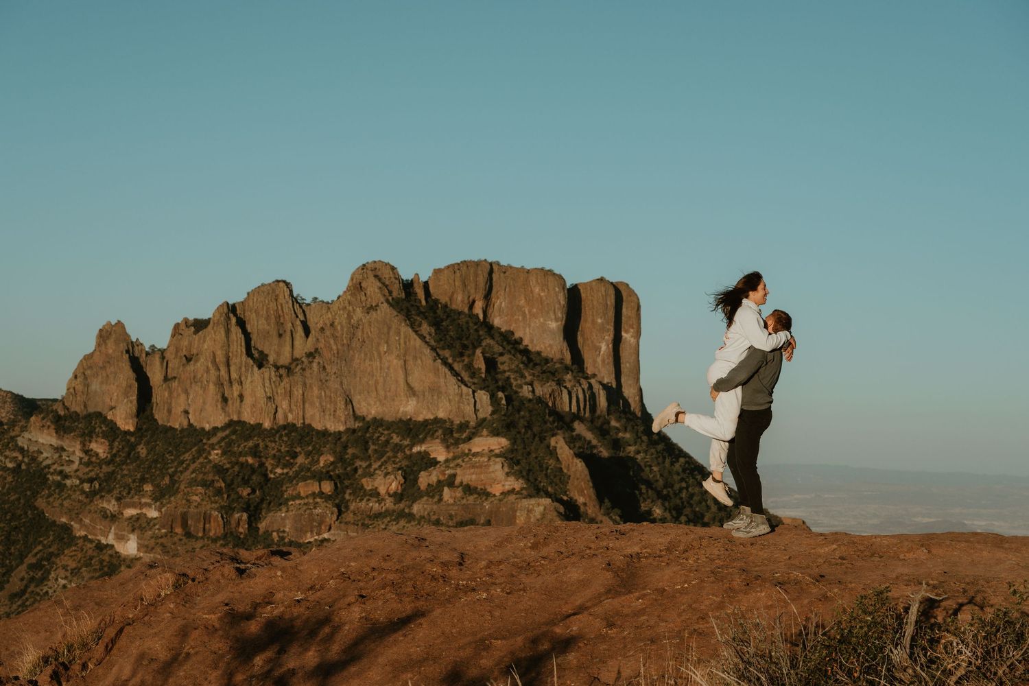 A couple enjoys a scenic mountain overlook during golden hour.