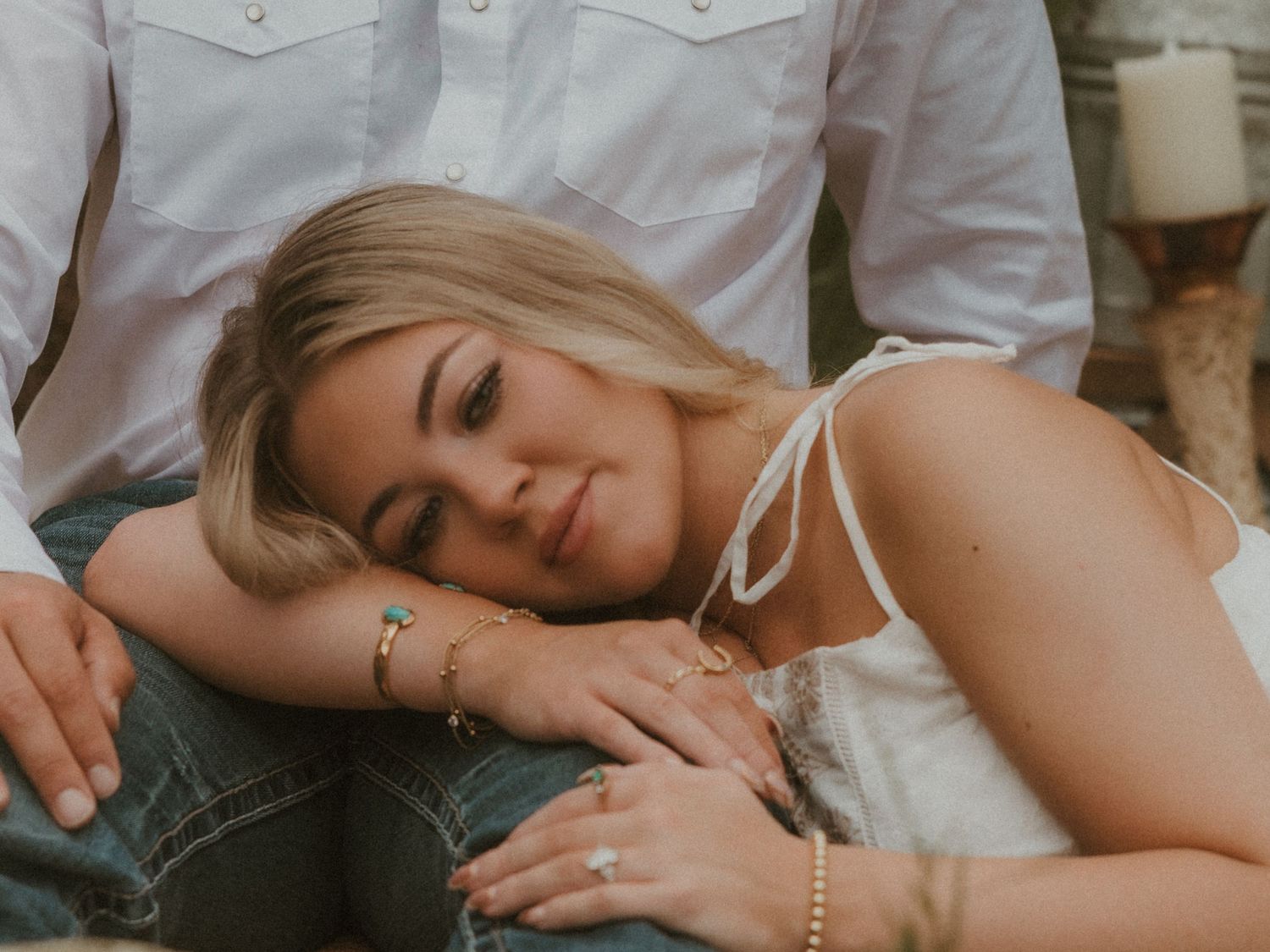 Couple sharing tender moments while resting on grass during countryside photoshoot.