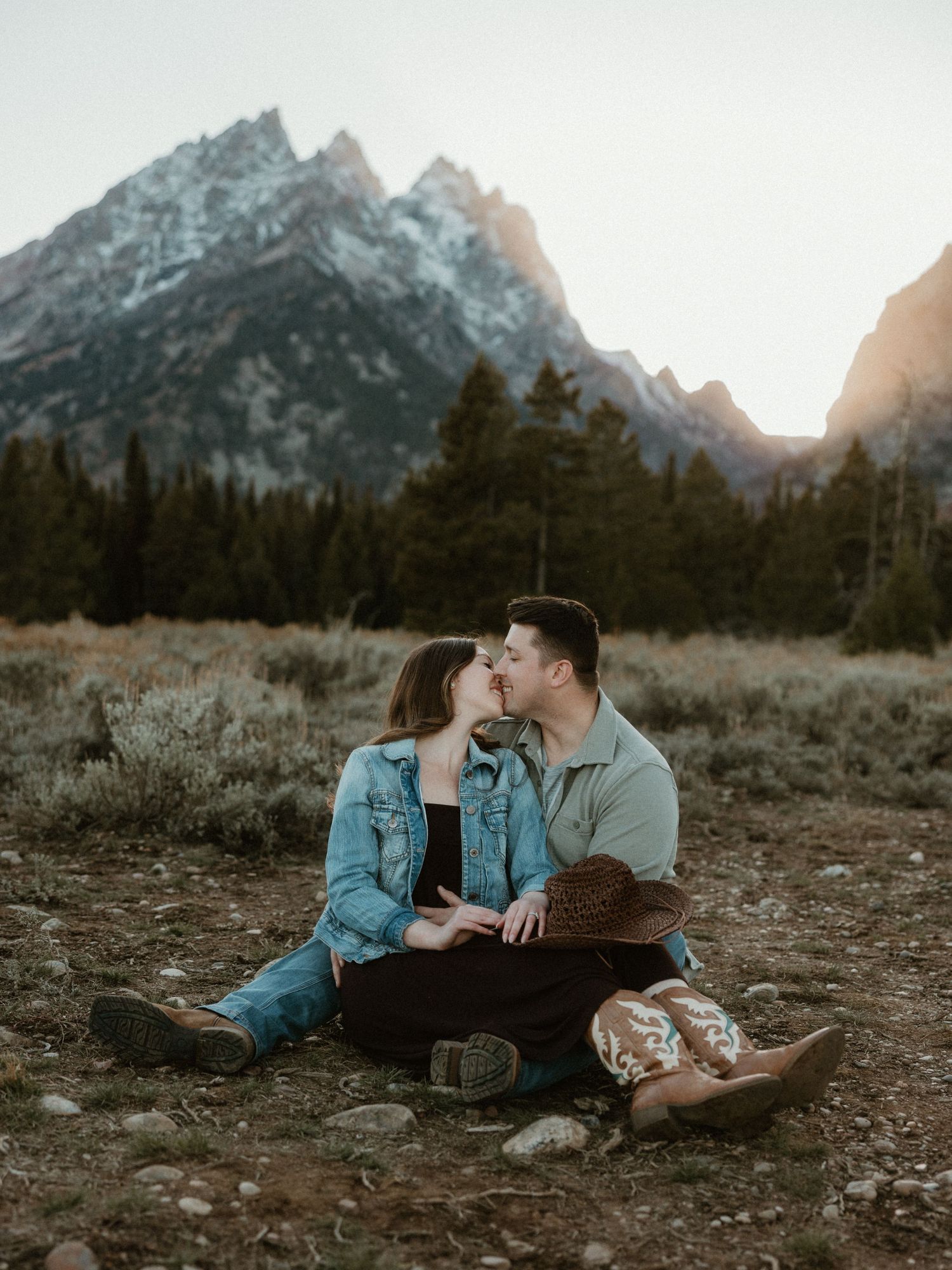 Couple relaxing on ground with scenic mountain vista behind them.