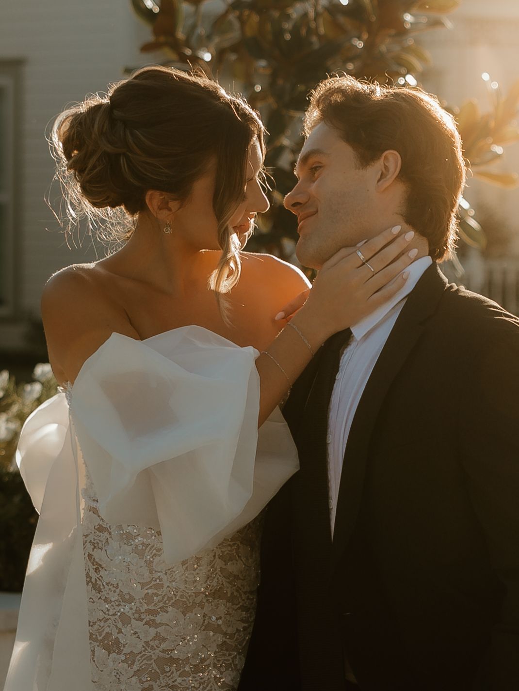 Romantic couple embraces in warm golden sunlight during sunset wedding photoshoot.