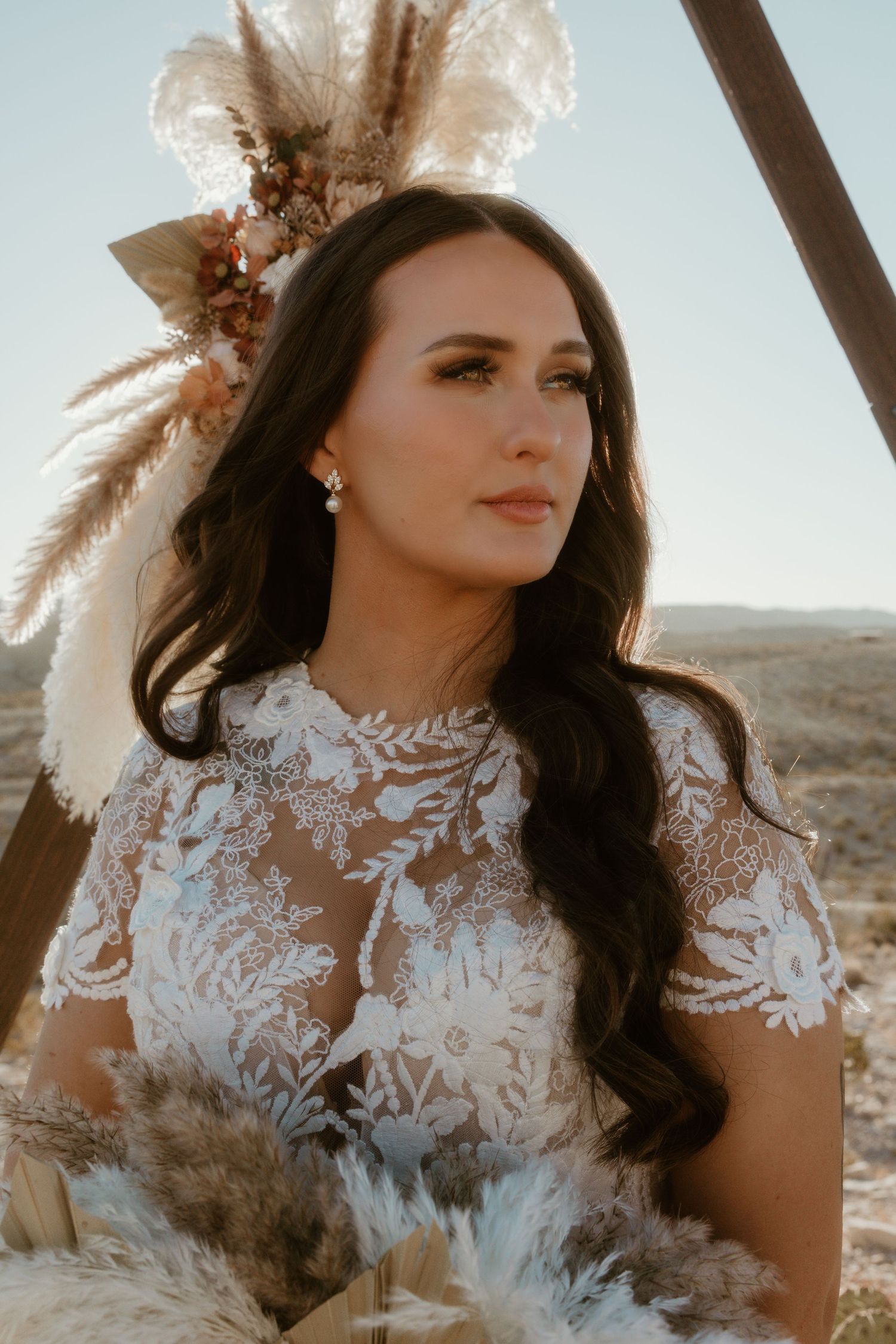 A lace wedding dress with pampas grass decorations in warm desert sunlight.