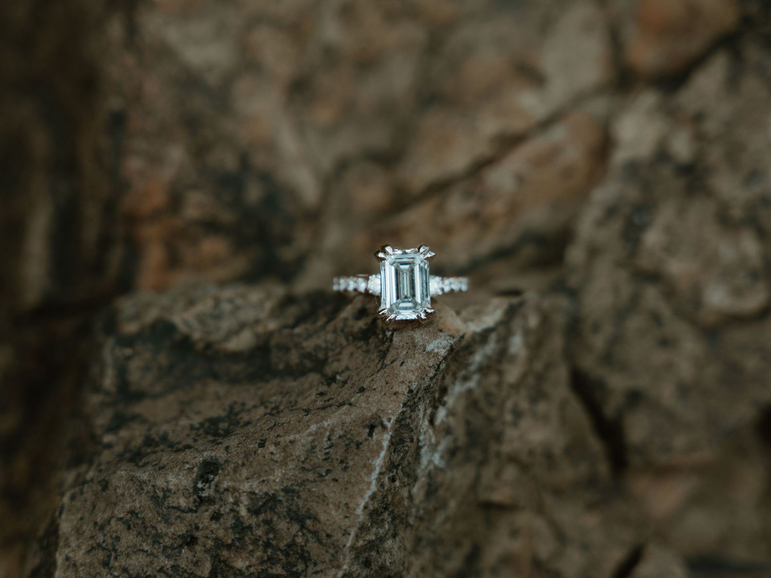 Diamond engagement ring photographed against textured stone background.