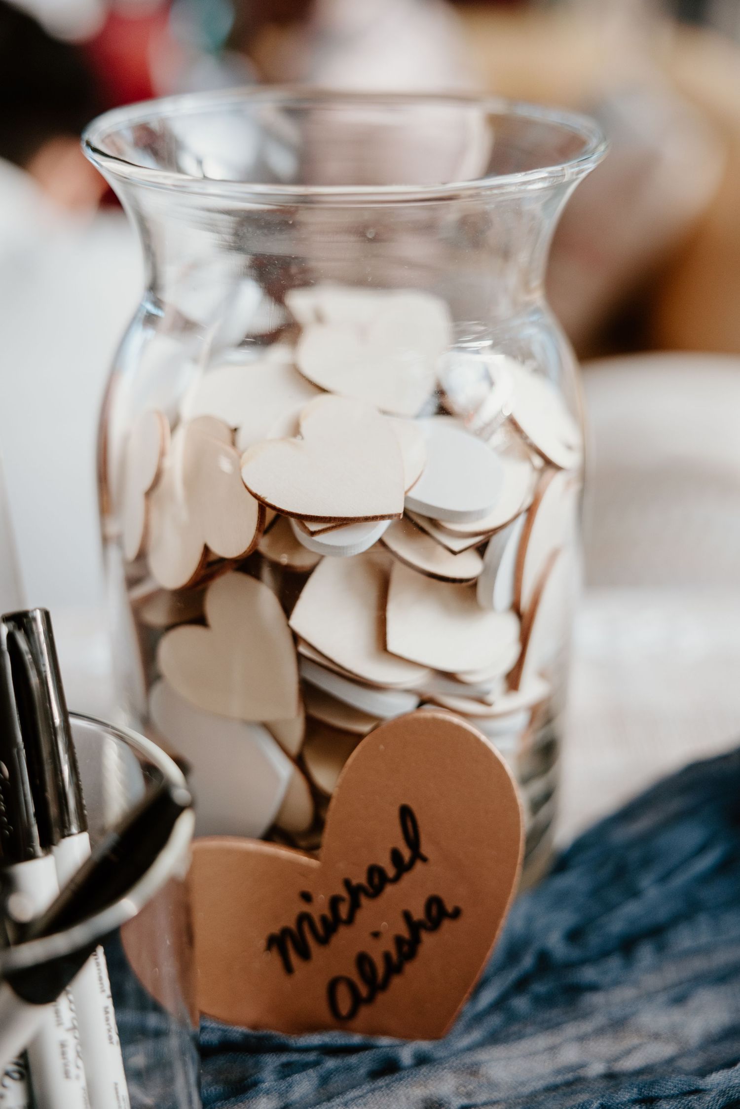 A glass jar filled with paper hearts for wedding messages and wishes.