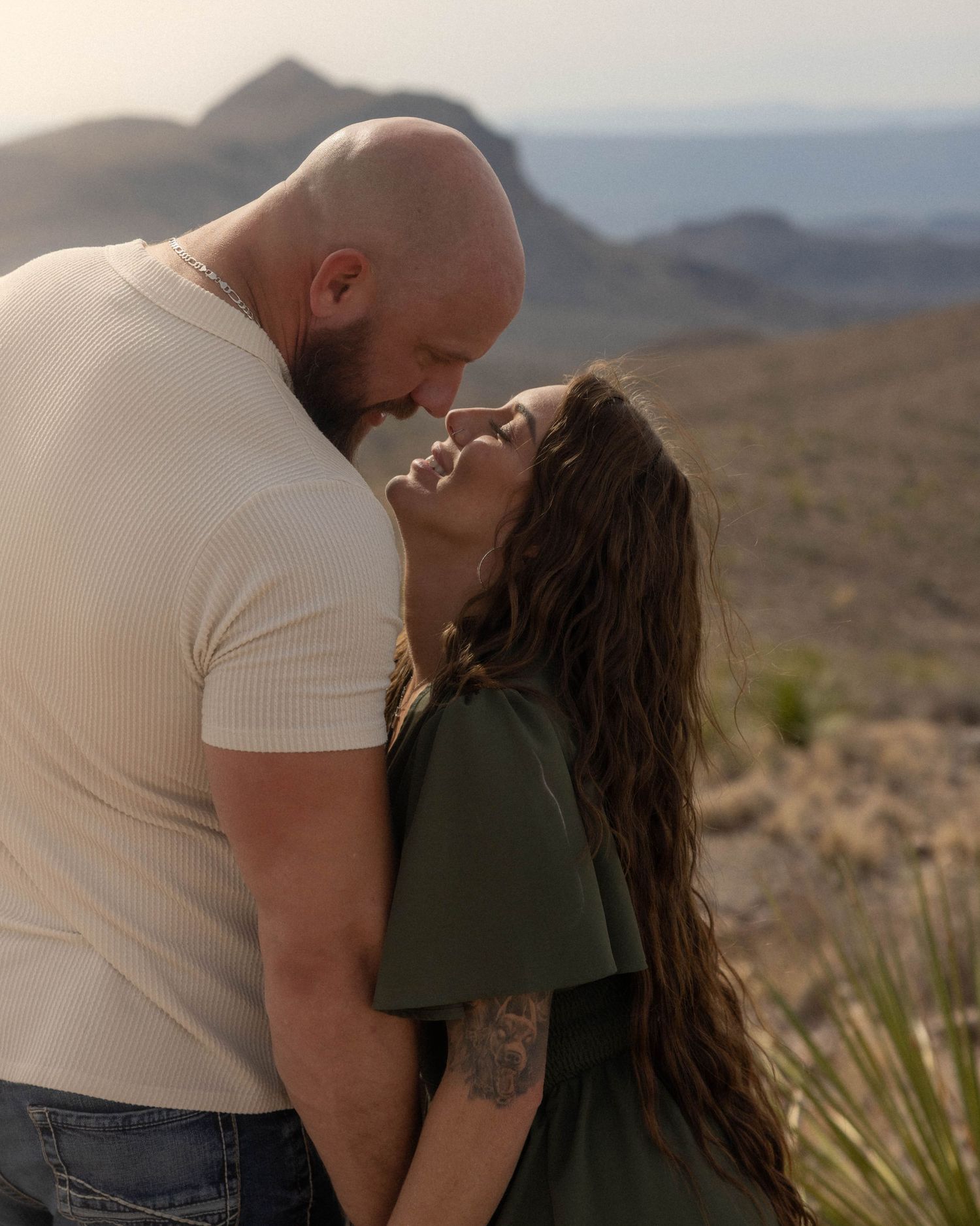 Two people share an intimate moment against a desert mountain backdrop.
