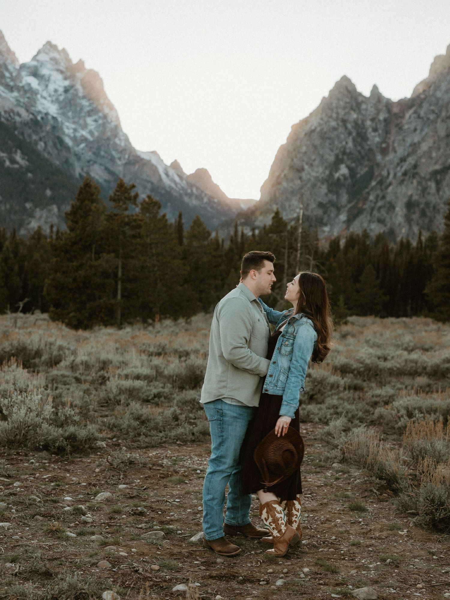 Romantic couple embracing in front of mountain landscape during sunset.