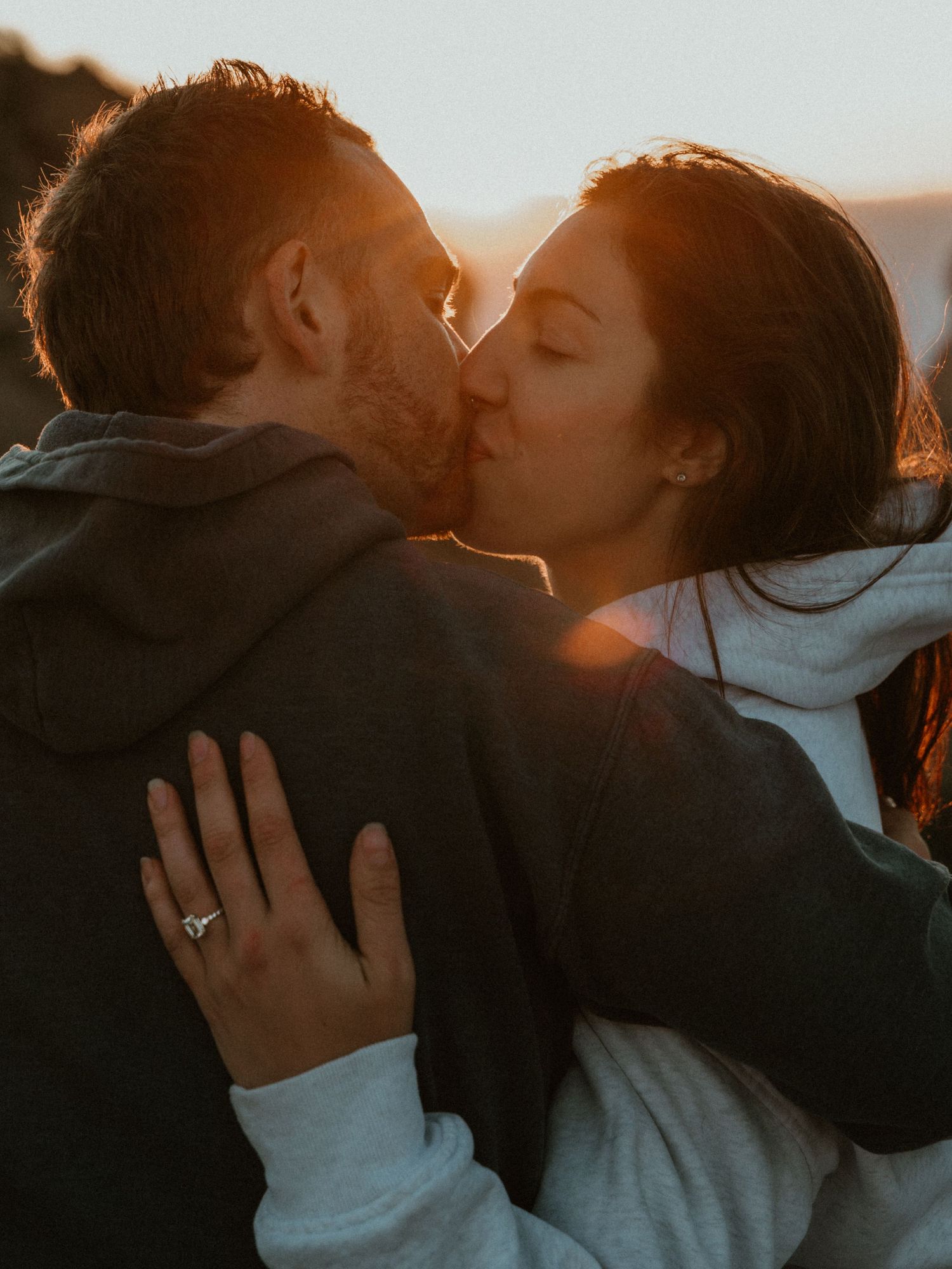 A romantic sunset embrace captured against a mountain backdrop.