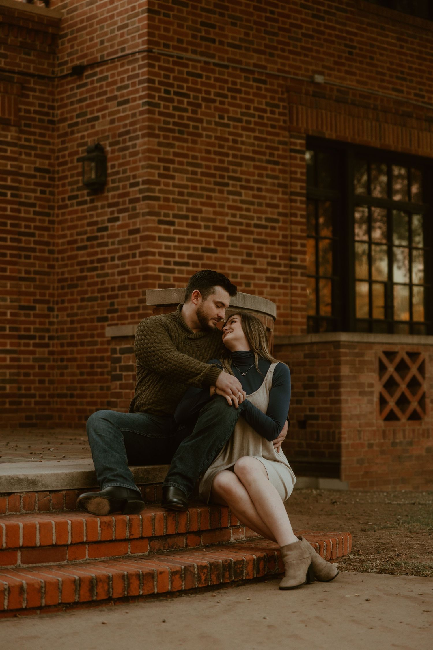 Couple sitting together on brick steps sharing romantic moment at sunset.