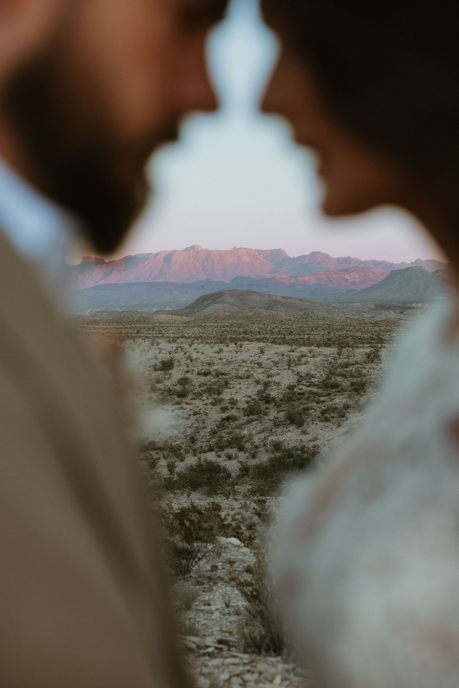Desert mountain landscape at dusk with silhouettes in the foreground.
