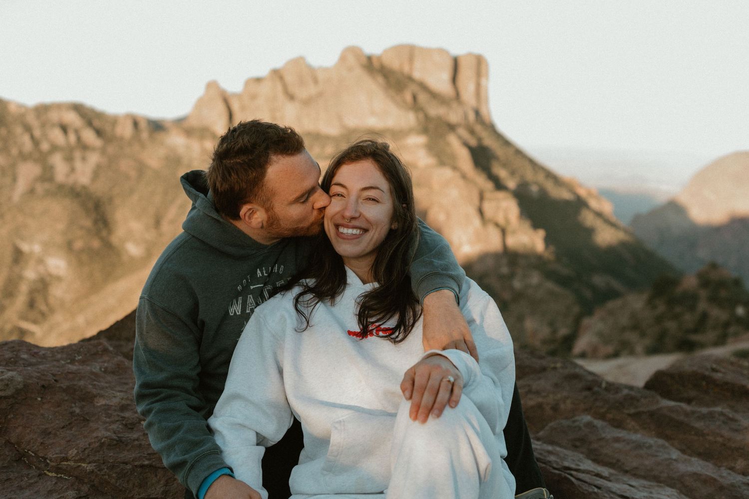 Two people share a happy moment together on a mountain ridge at sunset.