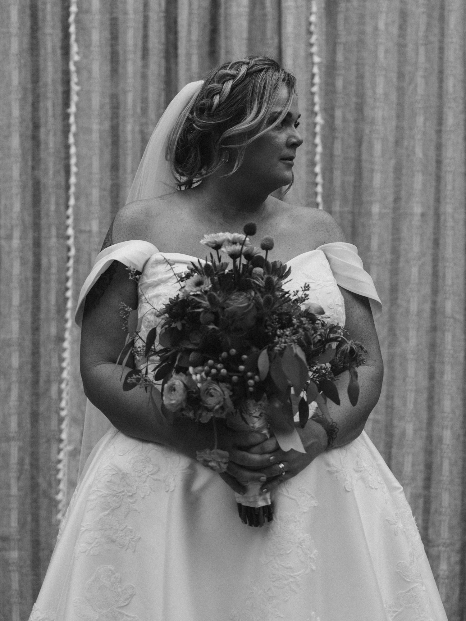 Bridal party holding beautiful autumn-toned bouquets against a white curtain backdrop.