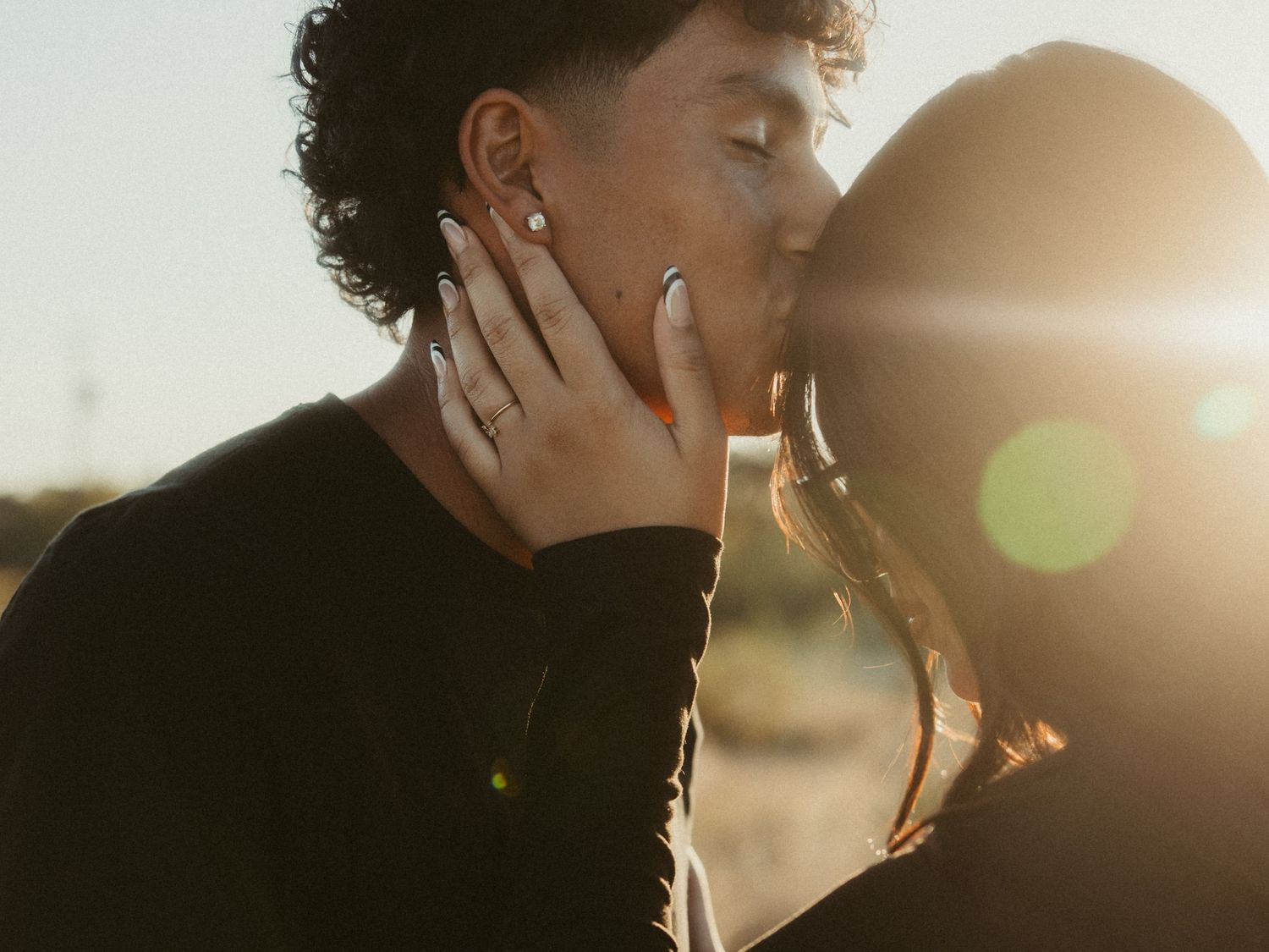 Intimate couple embraces in silhouette against bright sunlight creating a romantic backlit effect.
