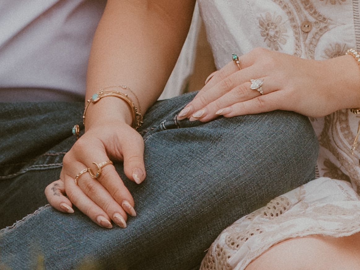 A couple's hands intertwined showing wedding rings in a romantic outdoor setting.