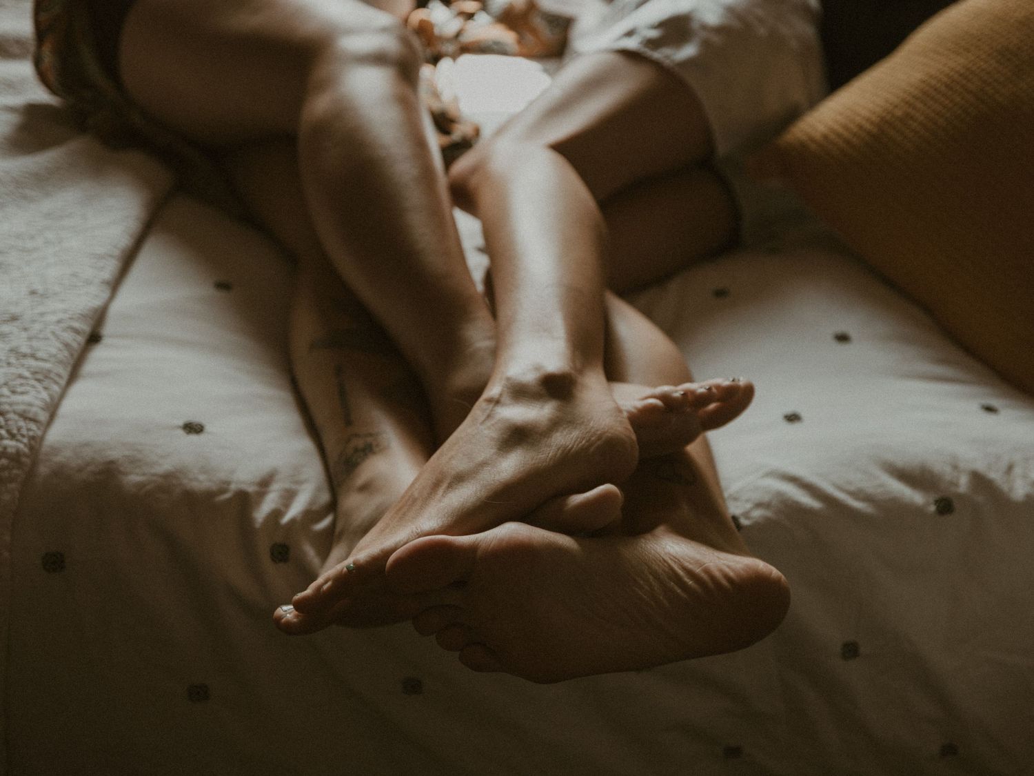 Intimate black and white photograph of people resting together on bedding.