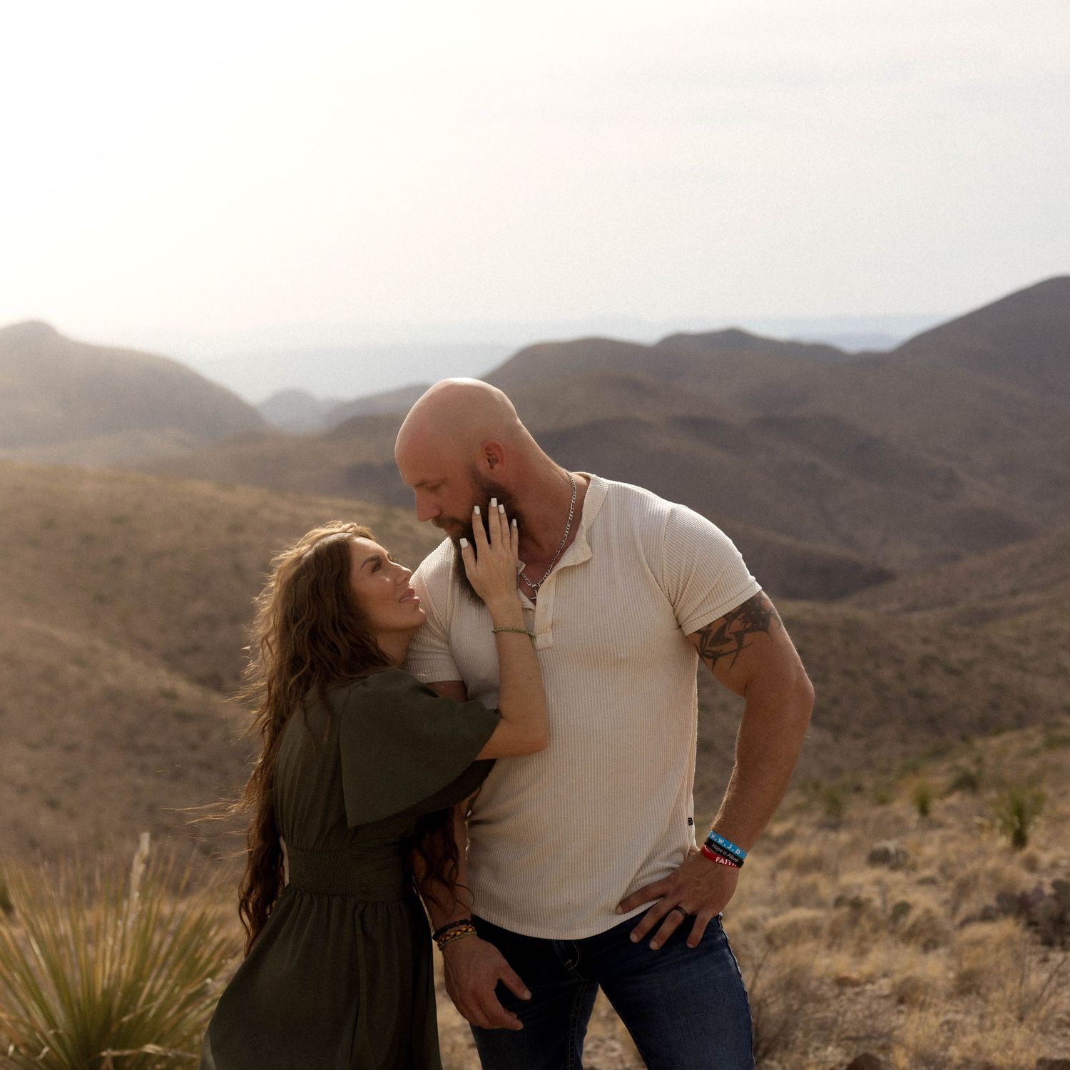 Couple embraces during an intimate desert photoshoot with mountains in background.