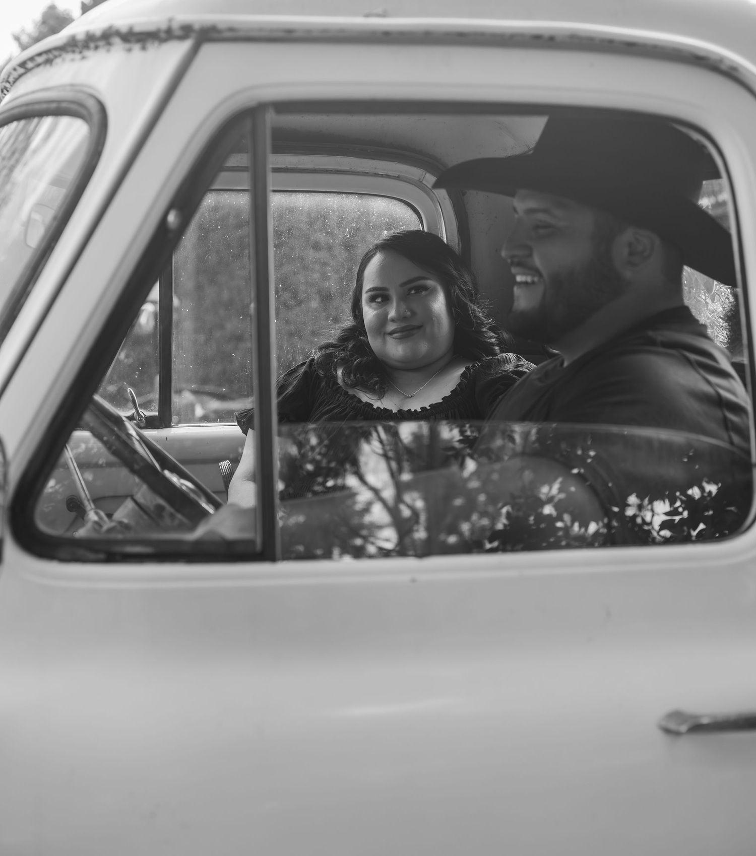 A series of black and white photographs showing people sitting in vintage cars viewed through the car windows.