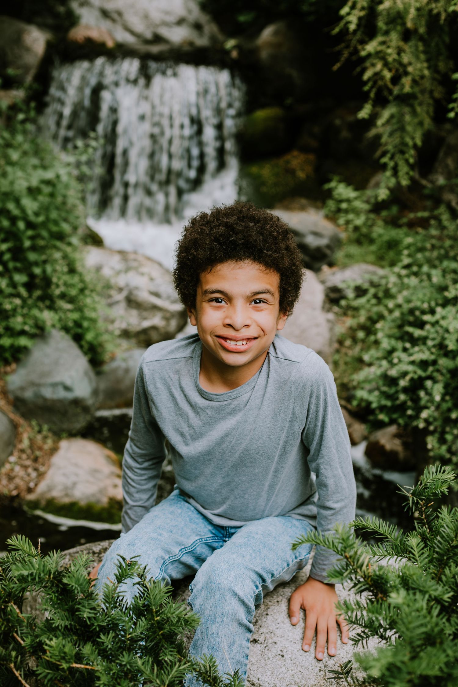 A joyful scene near a waterfall with lush greenery and rocks in a natural outdoor setting.