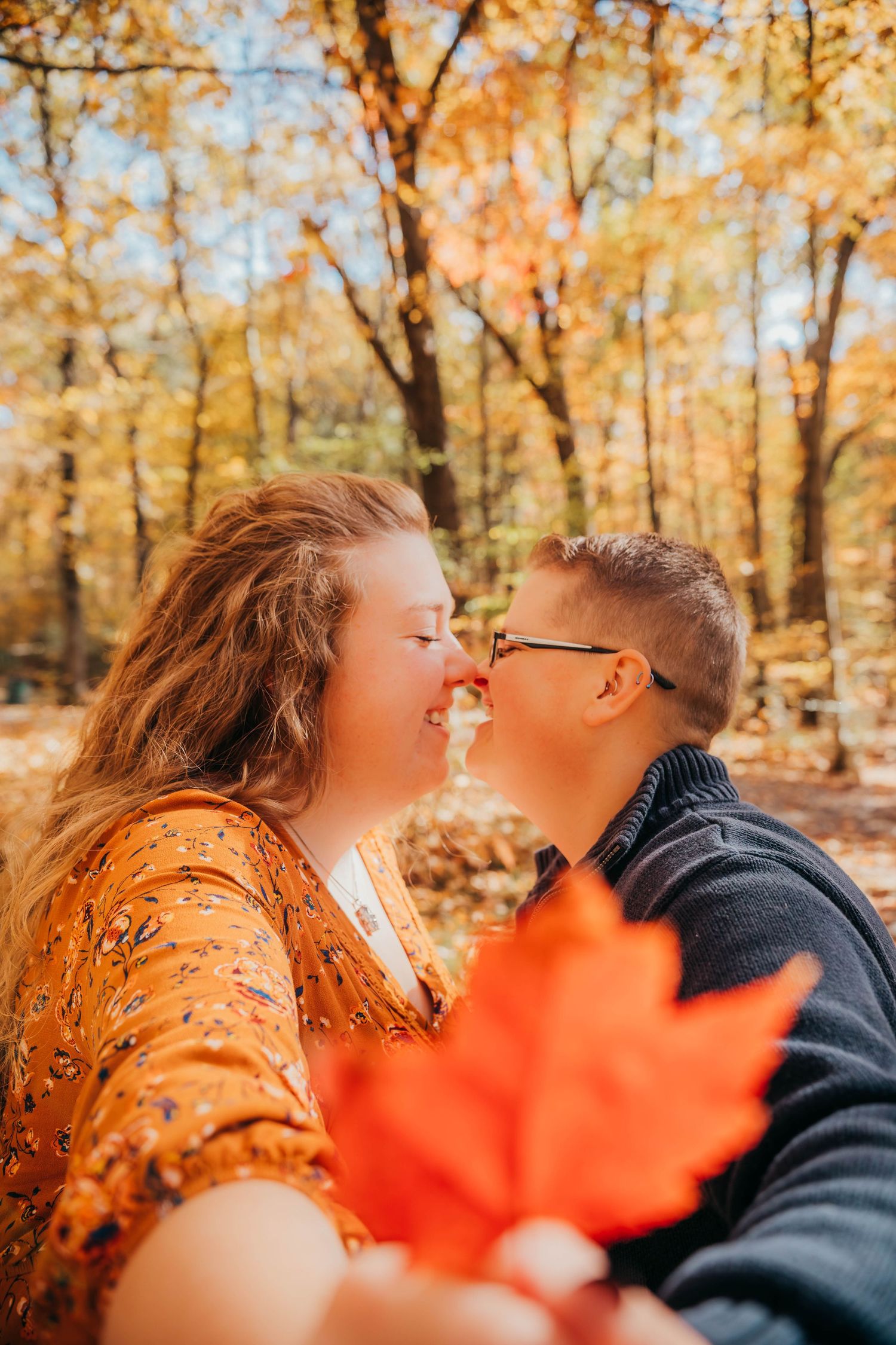 A romantic autumn scene with falling maple leaves in warm golden sunlight among trees in a park.