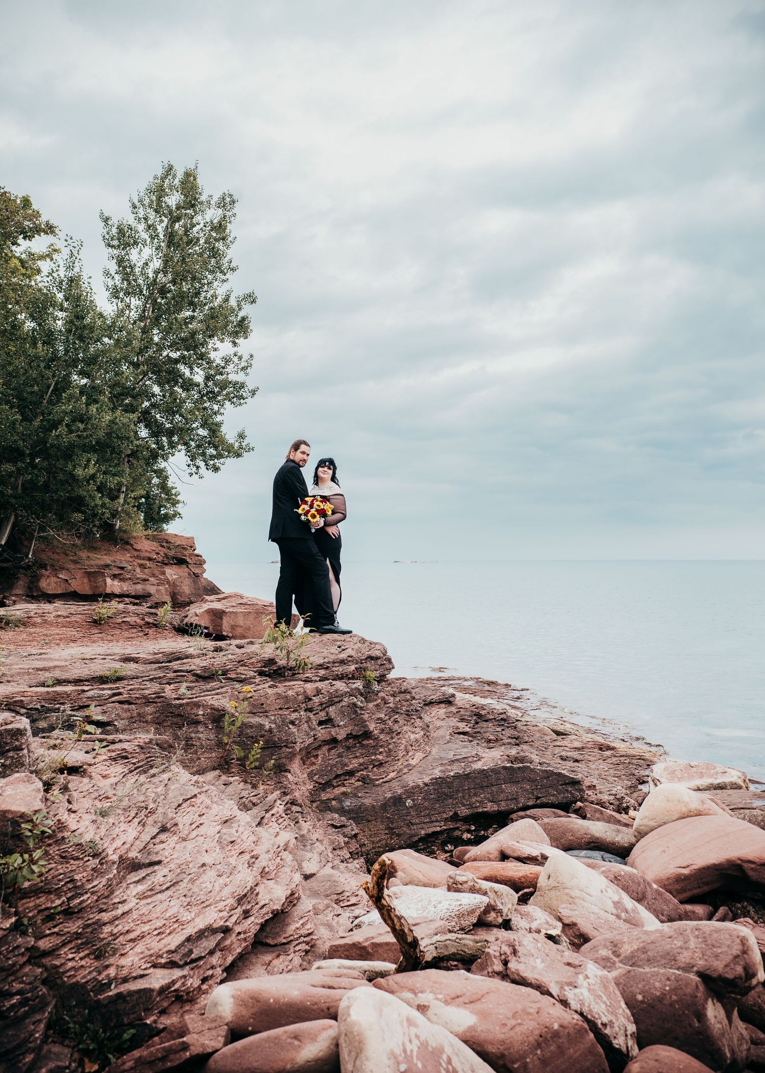 A series of photos showing a couple on red rock cliffs overlooking Lake Superior during a cloudy day.