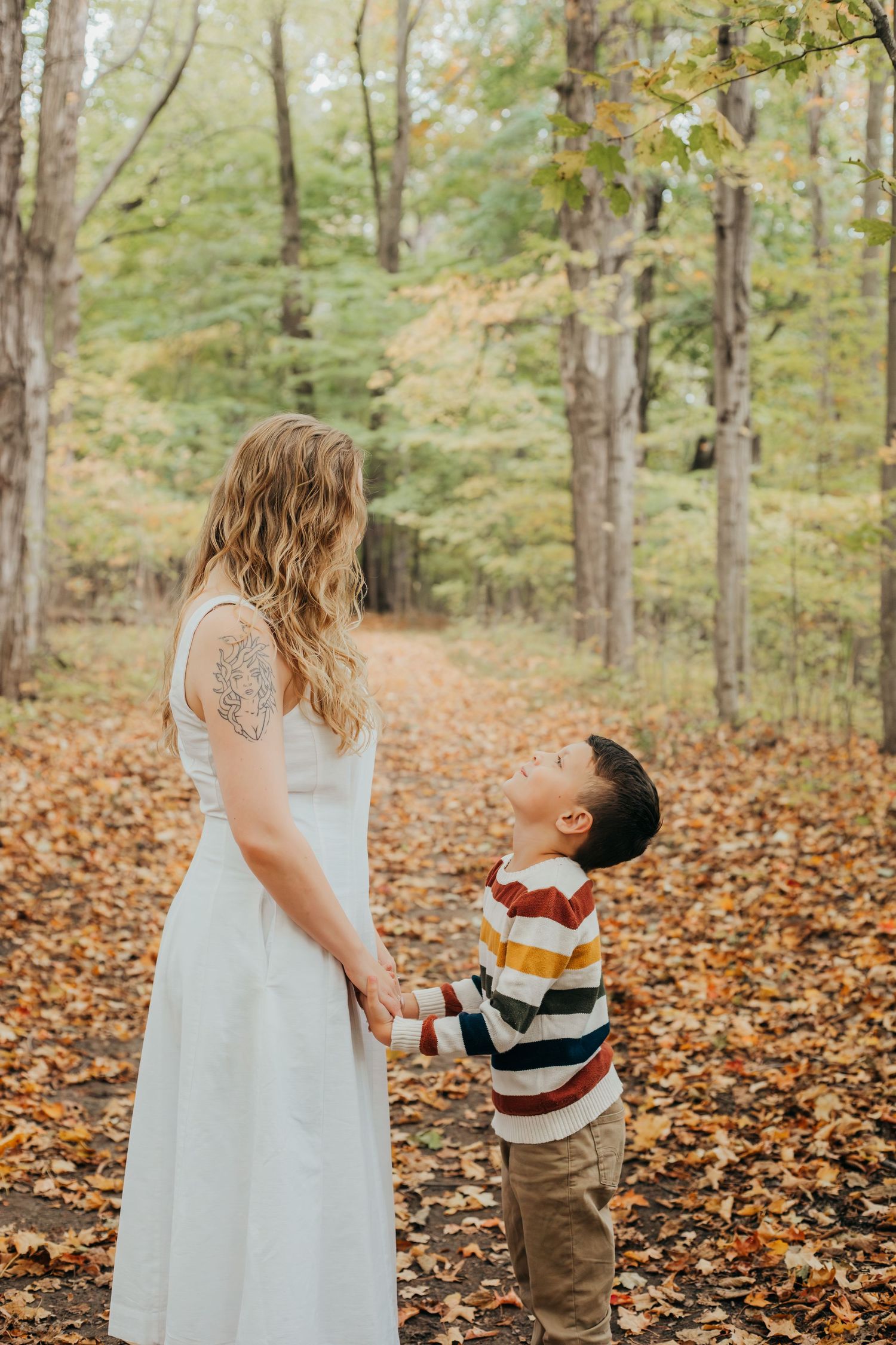 A series of four photos showing a tender moment between two people in a forest filled with autumn leaves.