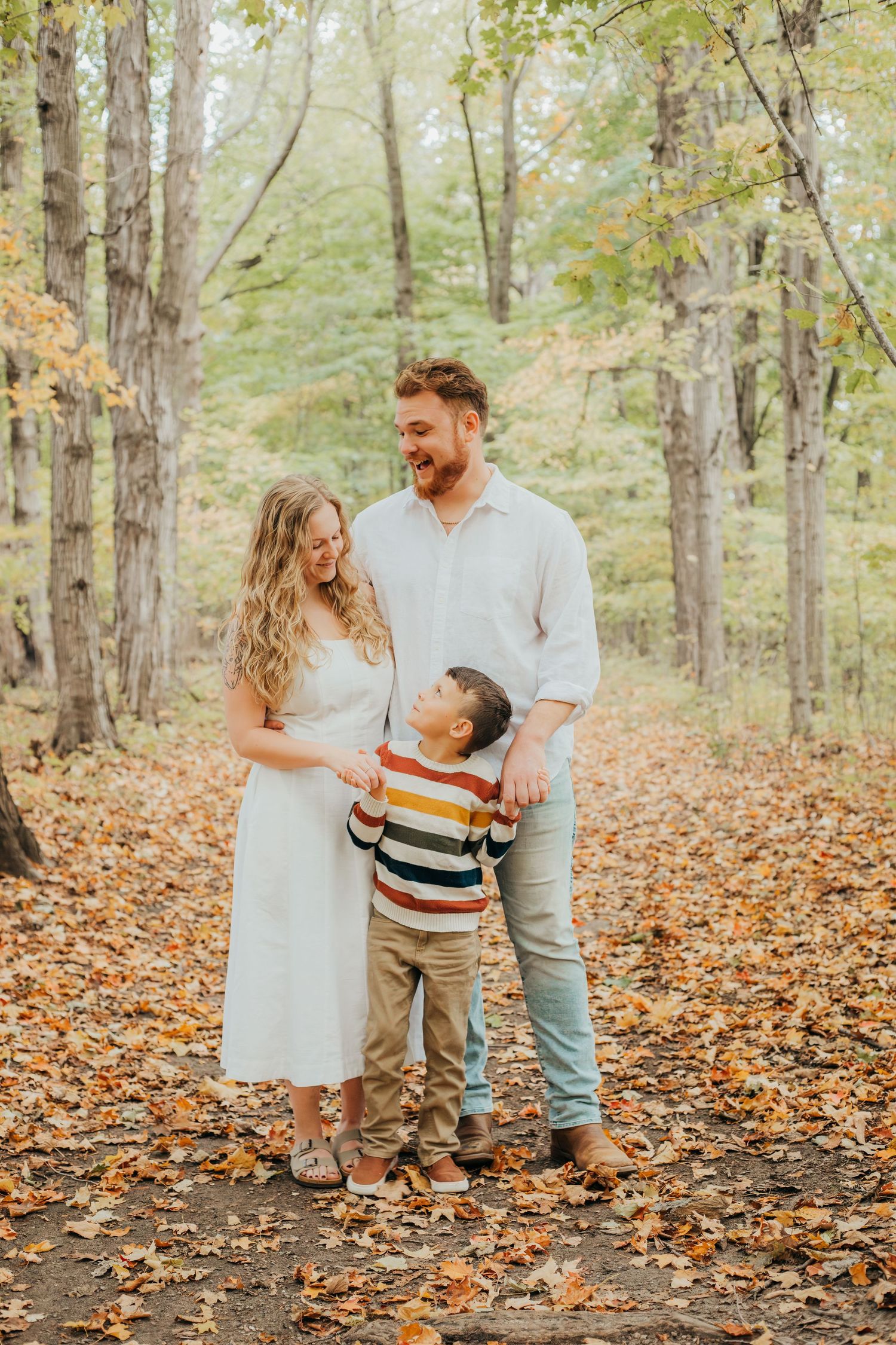 Family shares joyful moments together in an autumn forest filled with fallen leaves.