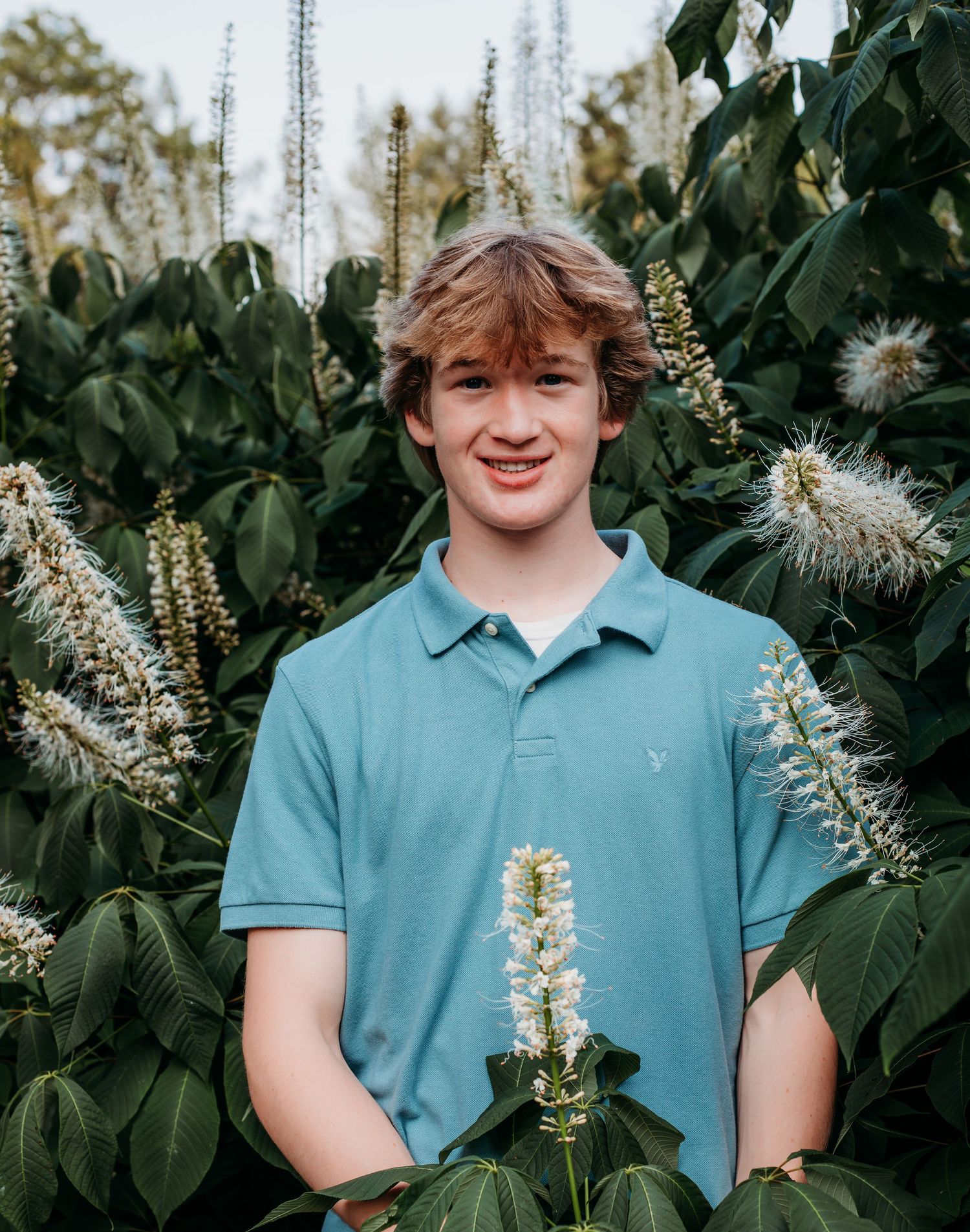 A series of four photos showing someone in a teal polo shirt standing among lush green foliage and white flowering plants.