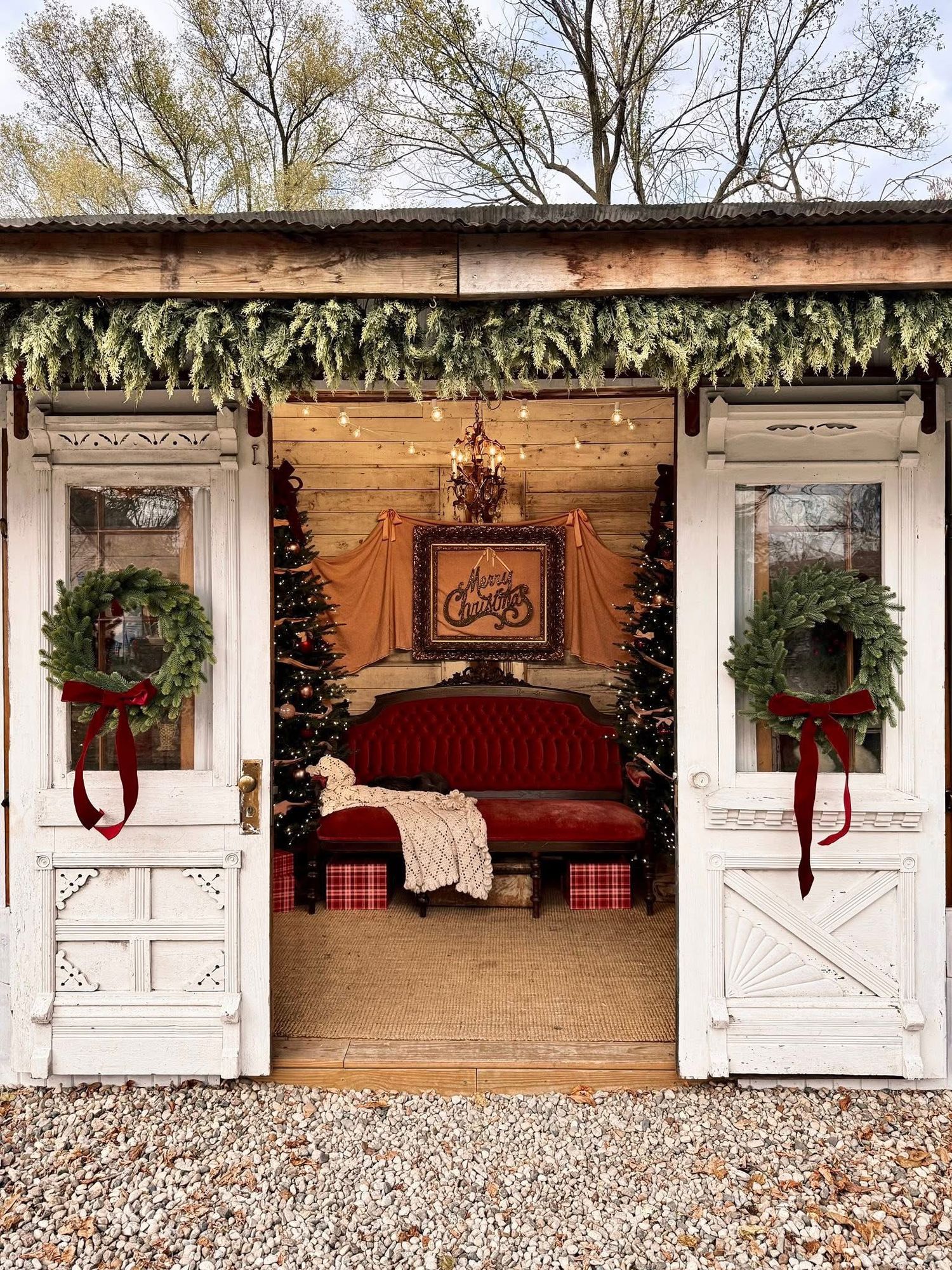 A row of vintage white ticket booth windows decorated with holiday wreaths and red bows at a historic venue.