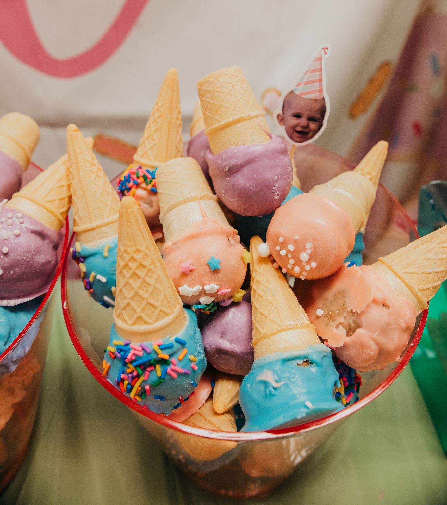 Colorful ice cream scoops decorated with sprinkles and chocolate dips served in waffle cones on display.