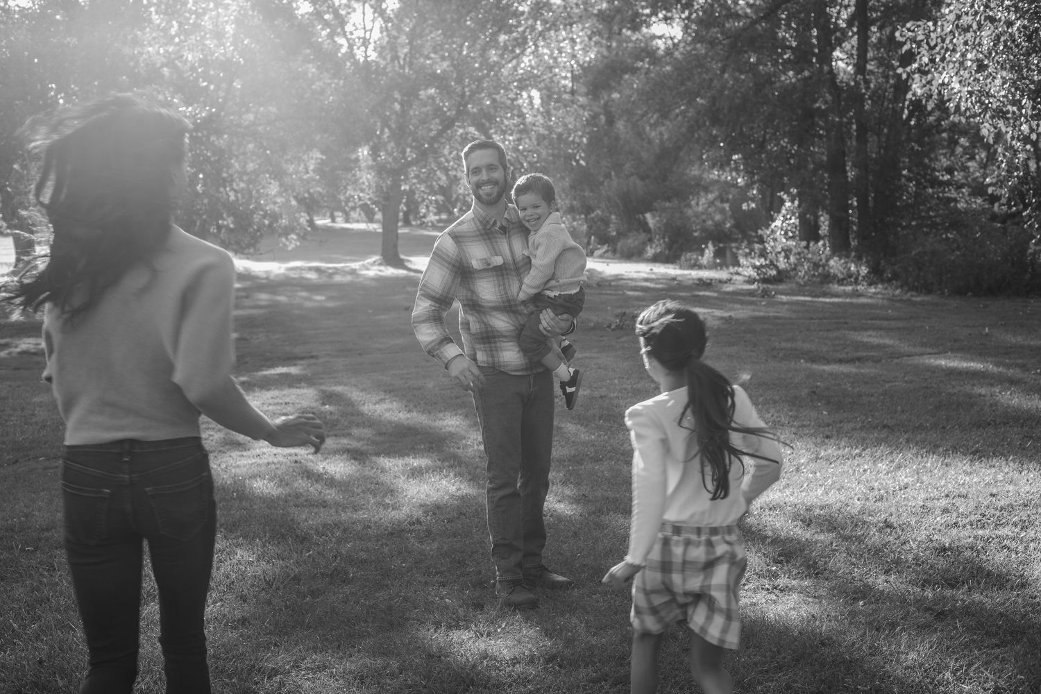 Black and white photo of a group playing together in a sunlit park on a summer afternoon.